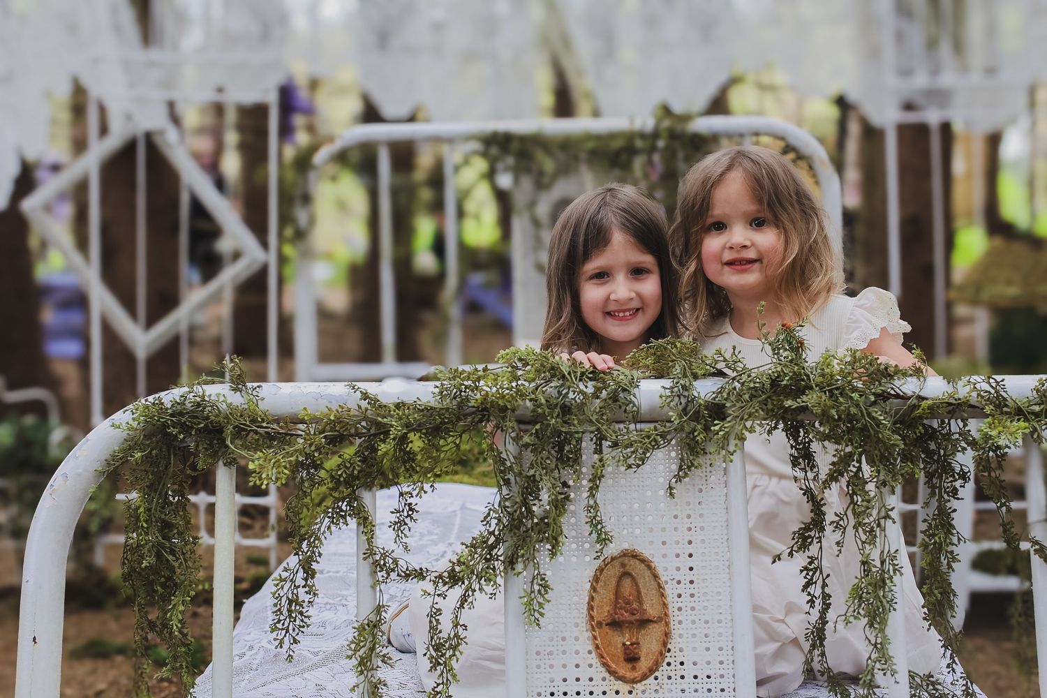 A white picket fence decorated with evergreen garland and string lights creates a festive holiday display.