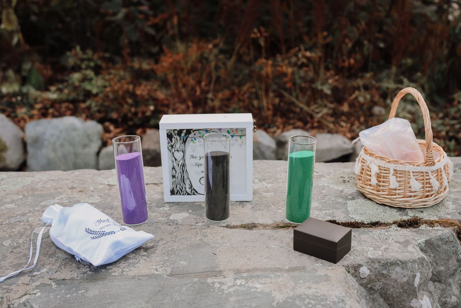 Water bottles, a framed photo, and a woven basket arranged on a stone surface in an outdoor setting.