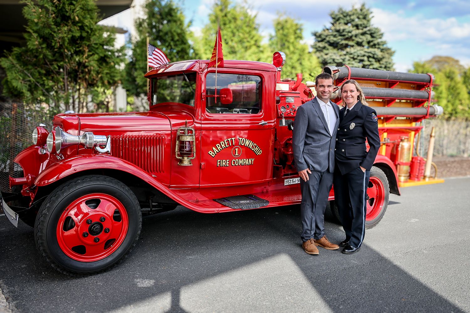 Couple posing in front of a vintage red Harveys Corners Fire Company truck with an American flag.