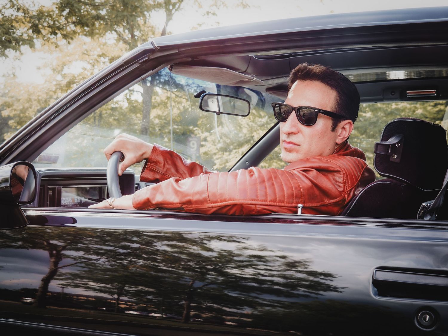 A sequence of images showing someone relaxing and reclining in the driver's seat of a parked car.