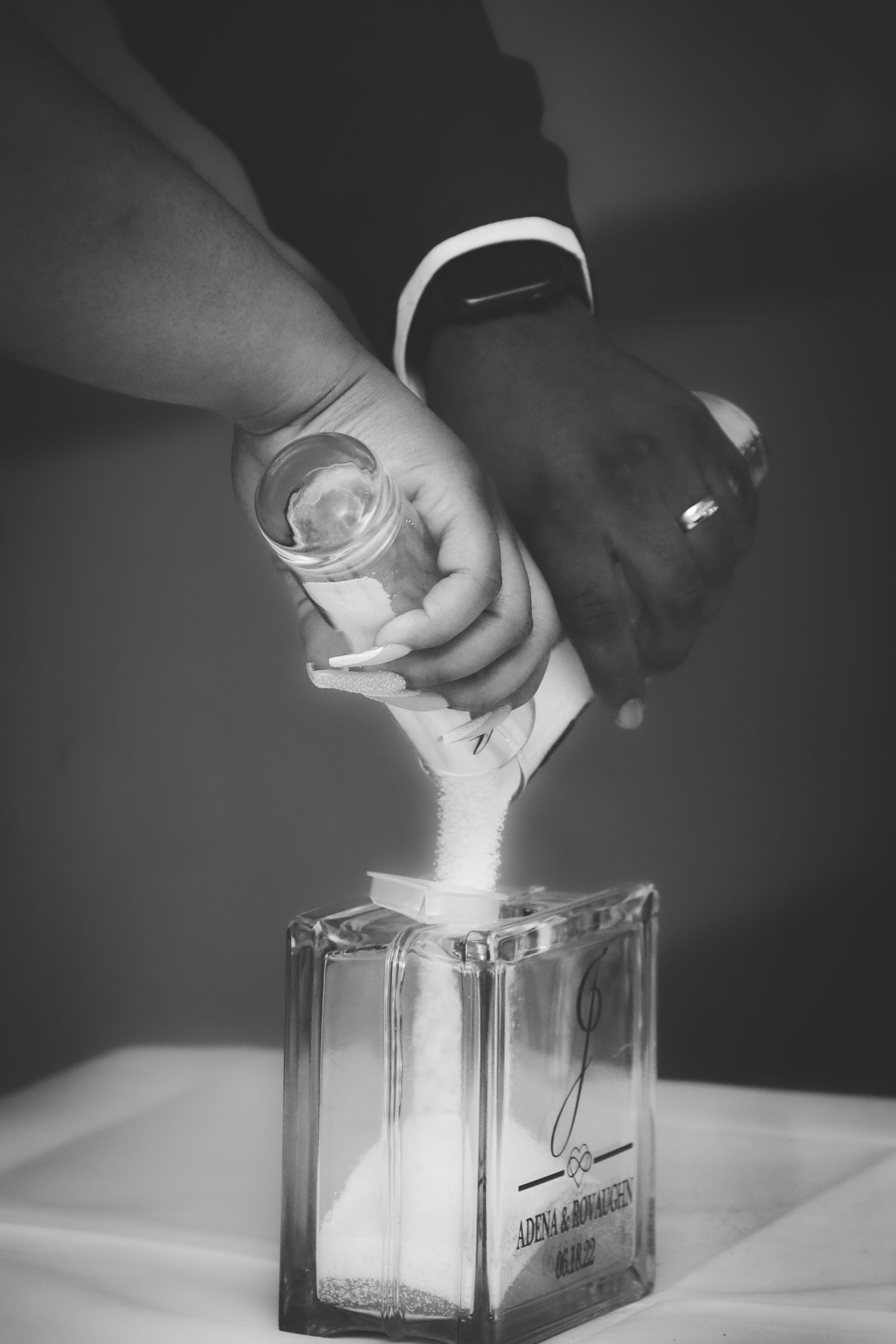 A sequence of black and white photos showing hands pouring milk into a glass container in dramatic lighting.