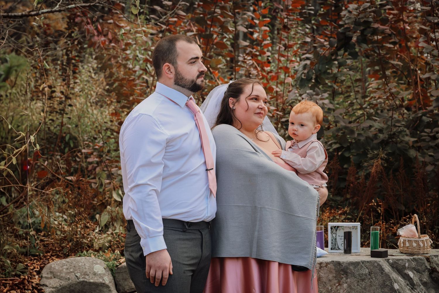 A romantic outdoor wedding celebration with guests gathered in a garden setting during autumn.