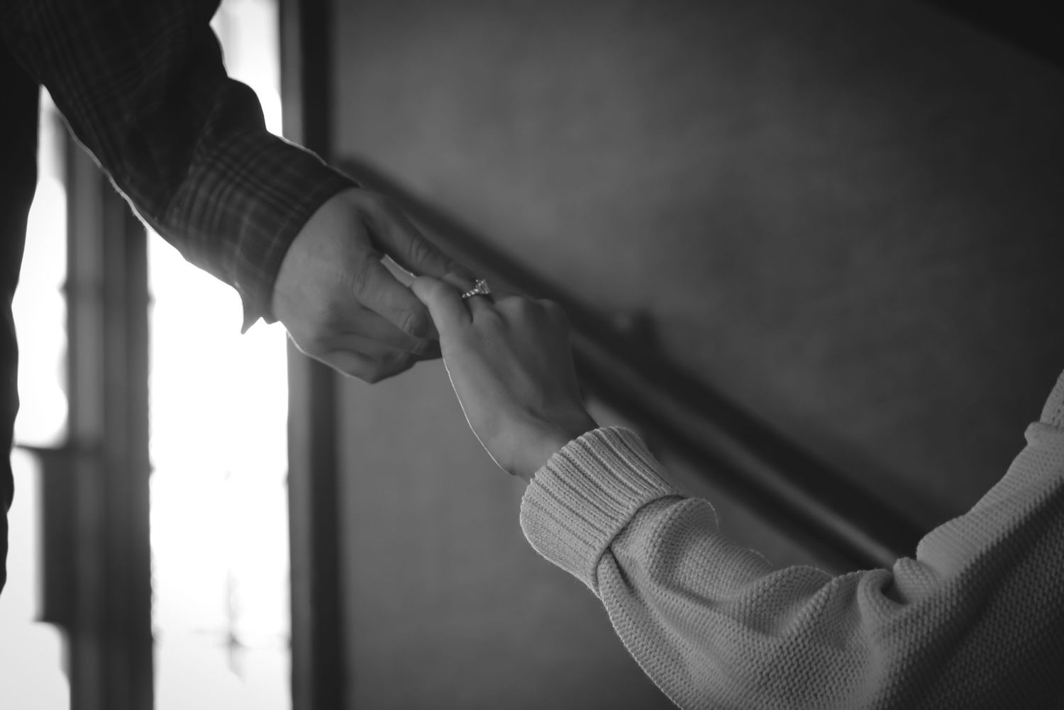 Black and white photo of a person's hands holding a pen and writing in a notebook.