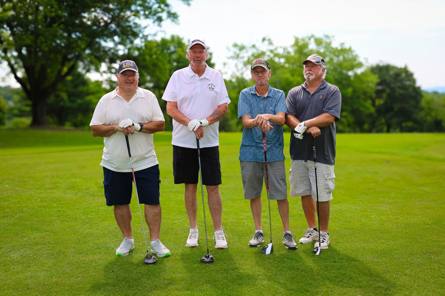 Group of golfers walking together on a lush green golf course during a sunny summer day.