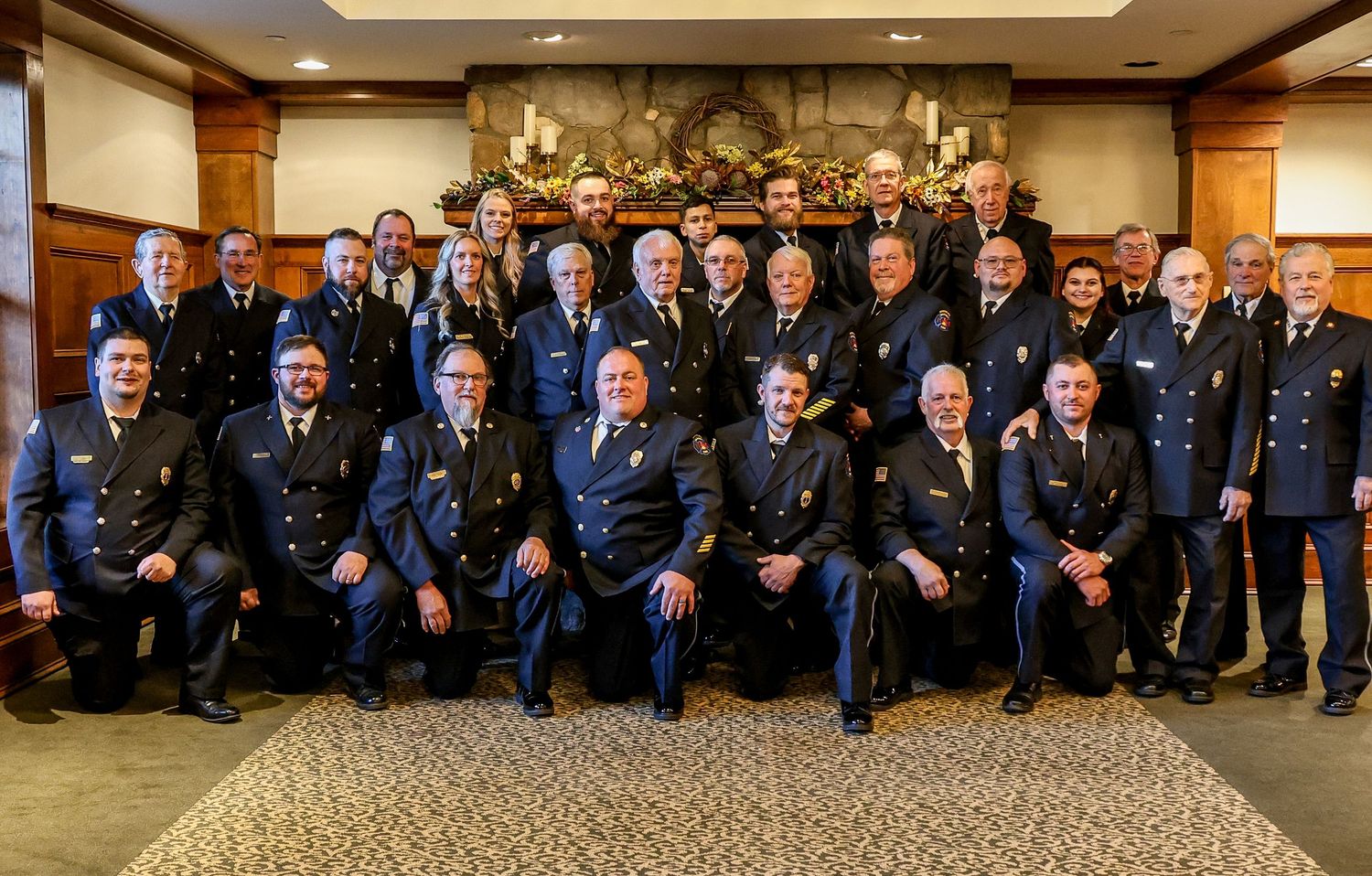 Large group of uniformed military service members gathered for a panoramic formal group photo in an indoor setting.