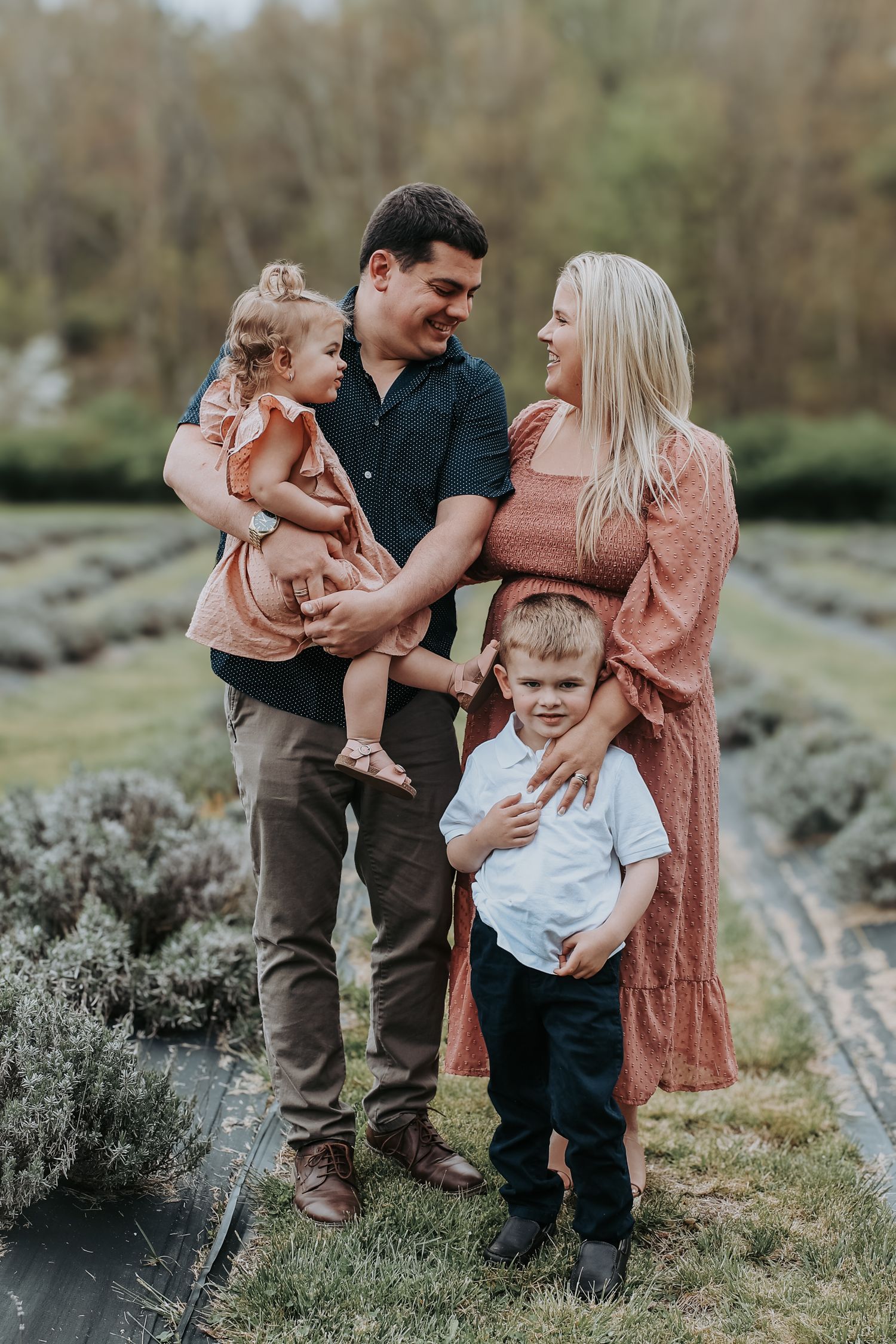 Family shares tender moments together outdoors in a natural setting with greenery and rocks in the background.