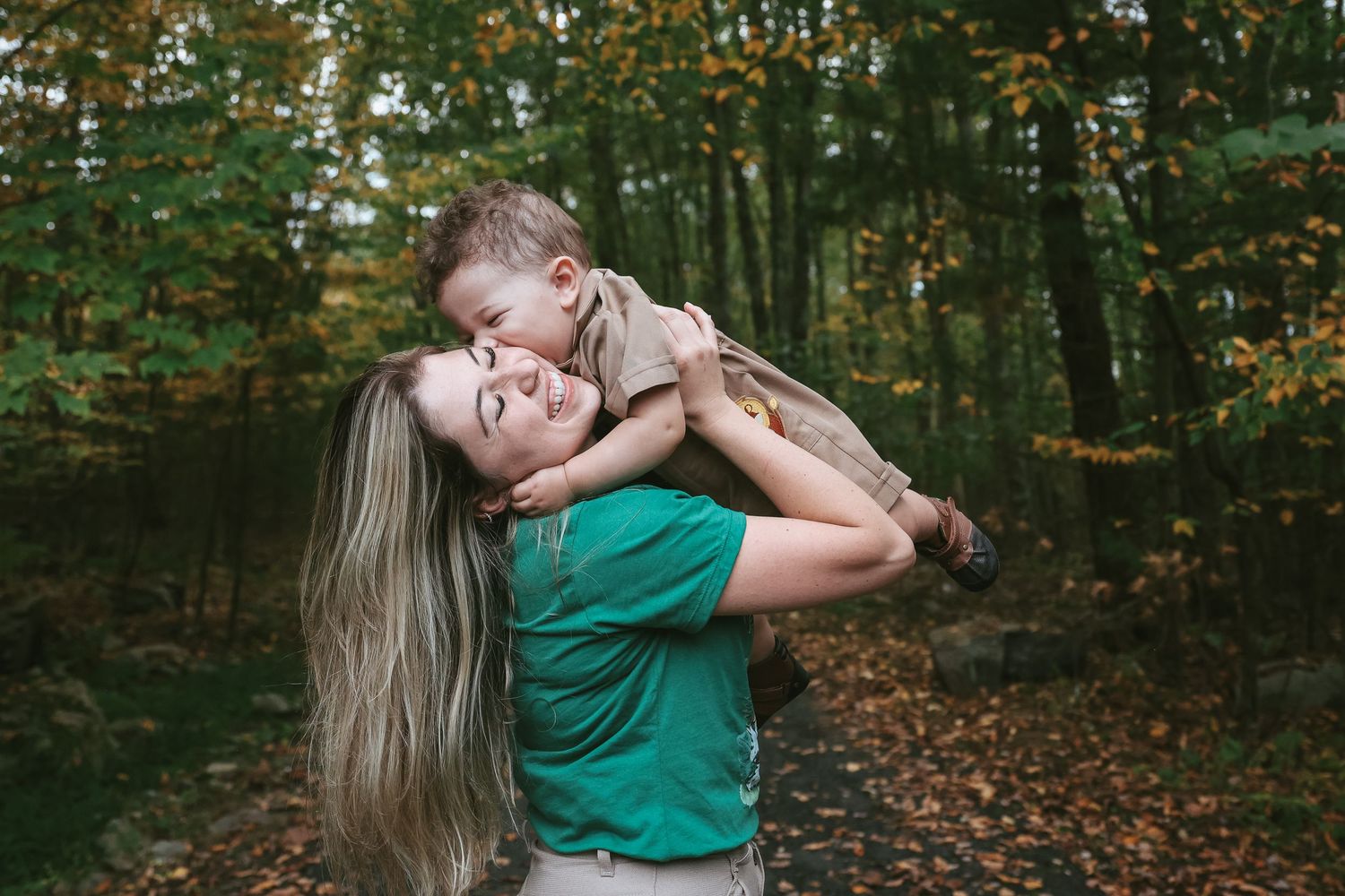 A joyful moment shared between parent and child playing together in an autumn forest setting.