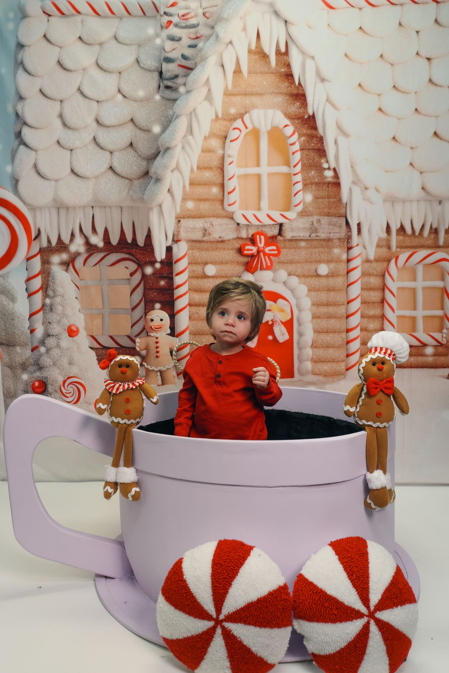 A festive holiday photo studio setup with candy cane decorations, peppermint props and a gingerbread house backdrop.