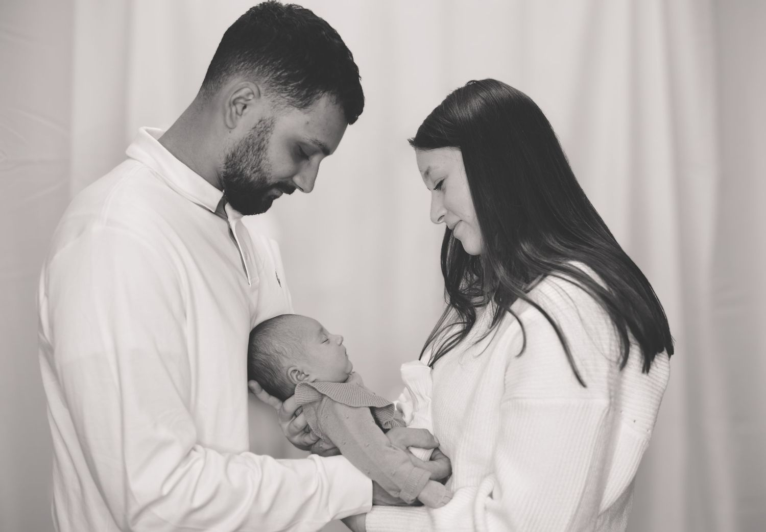 Black and white photo series showing tender moments between parents and their newborn baby in a medical setting.