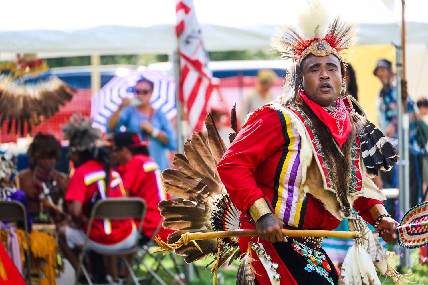 Native American dancers in traditional red regalia perform at a vibrant cultural festival celebration.