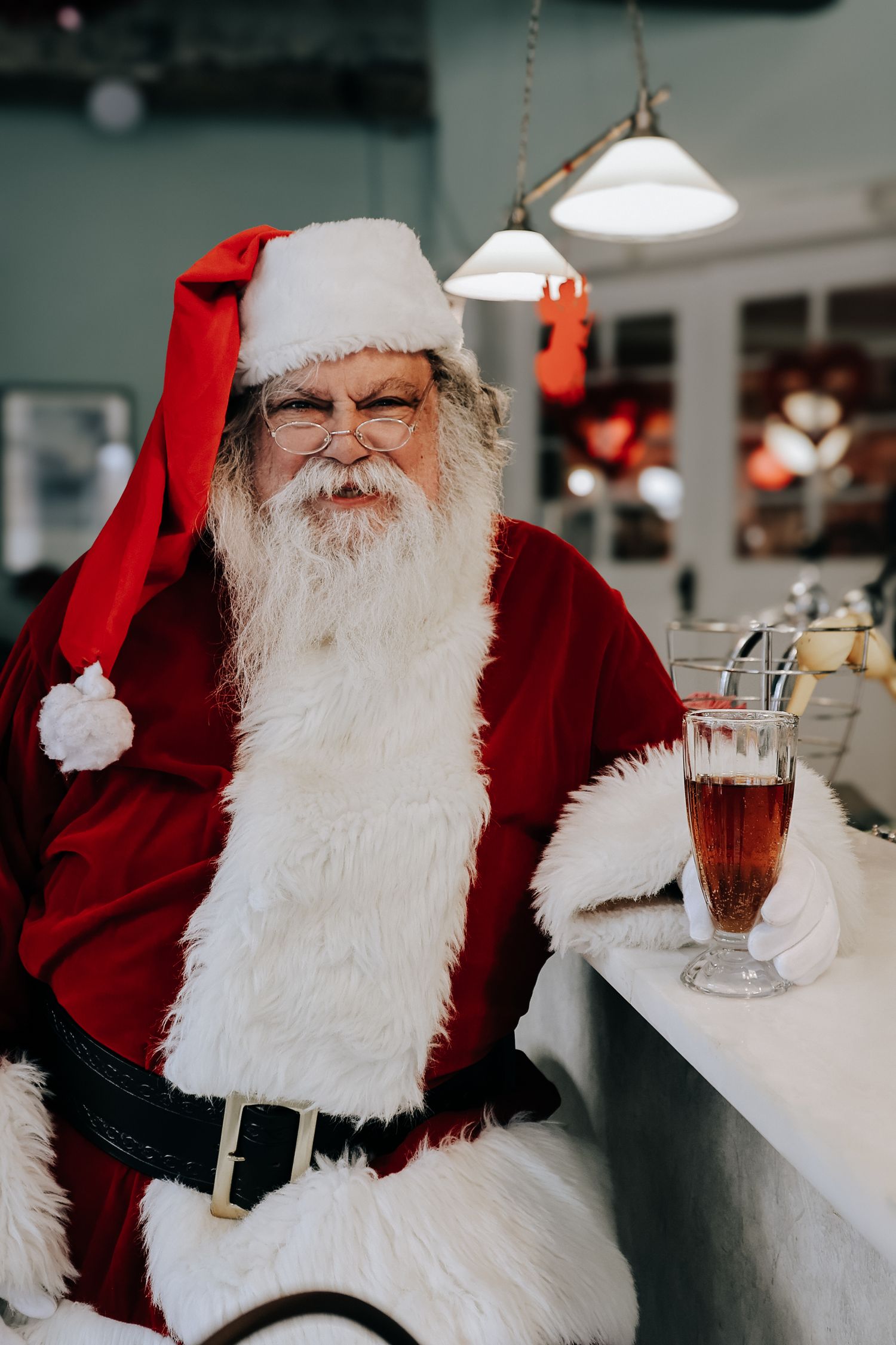 Someone wearing a traditional red and white Santa Claus costume sits at a counter with a festive drink nearby.