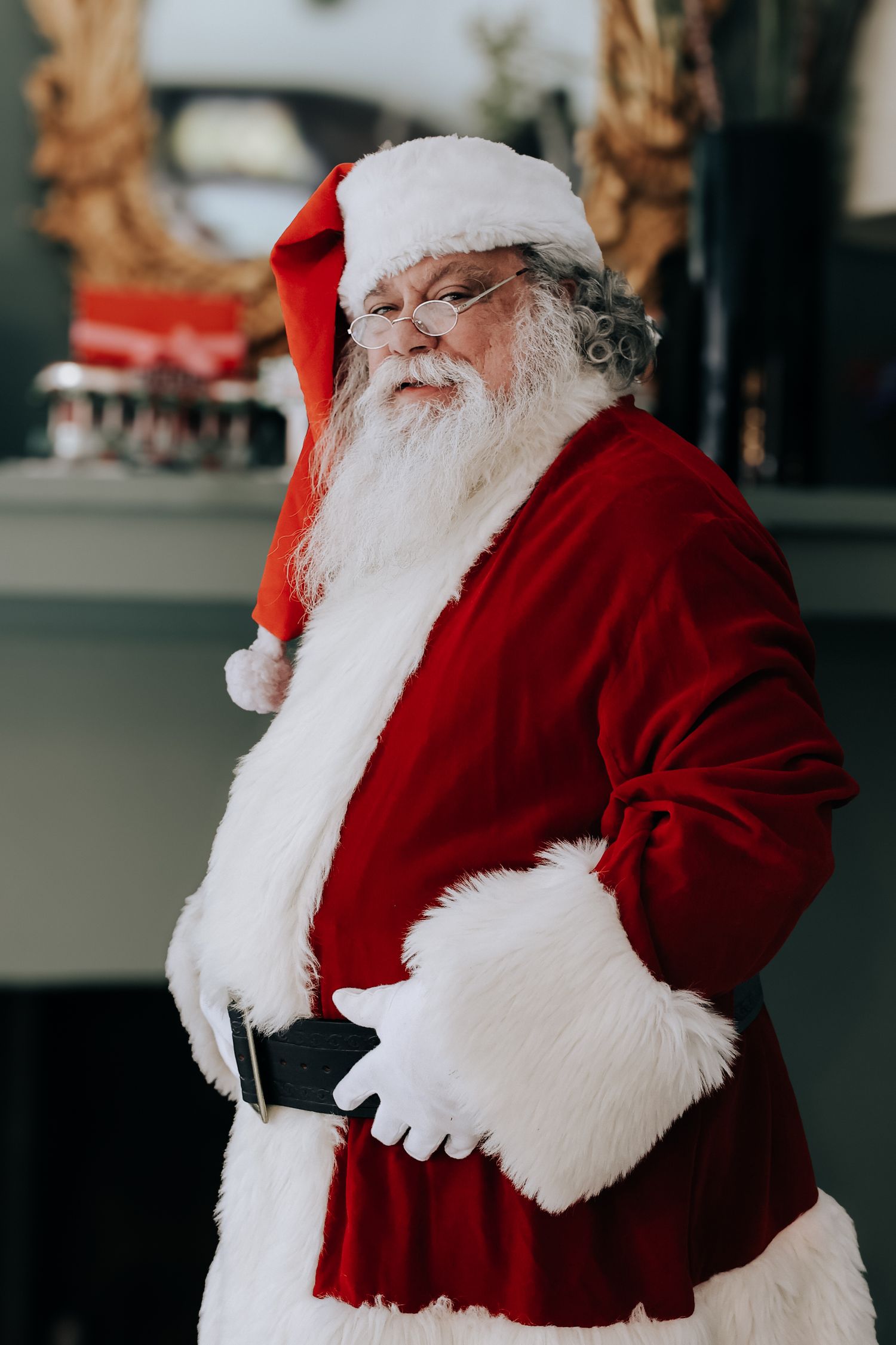 Santa Claus in traditional red velvet suit and white gloves laughs heartily in a candid photo sequence.