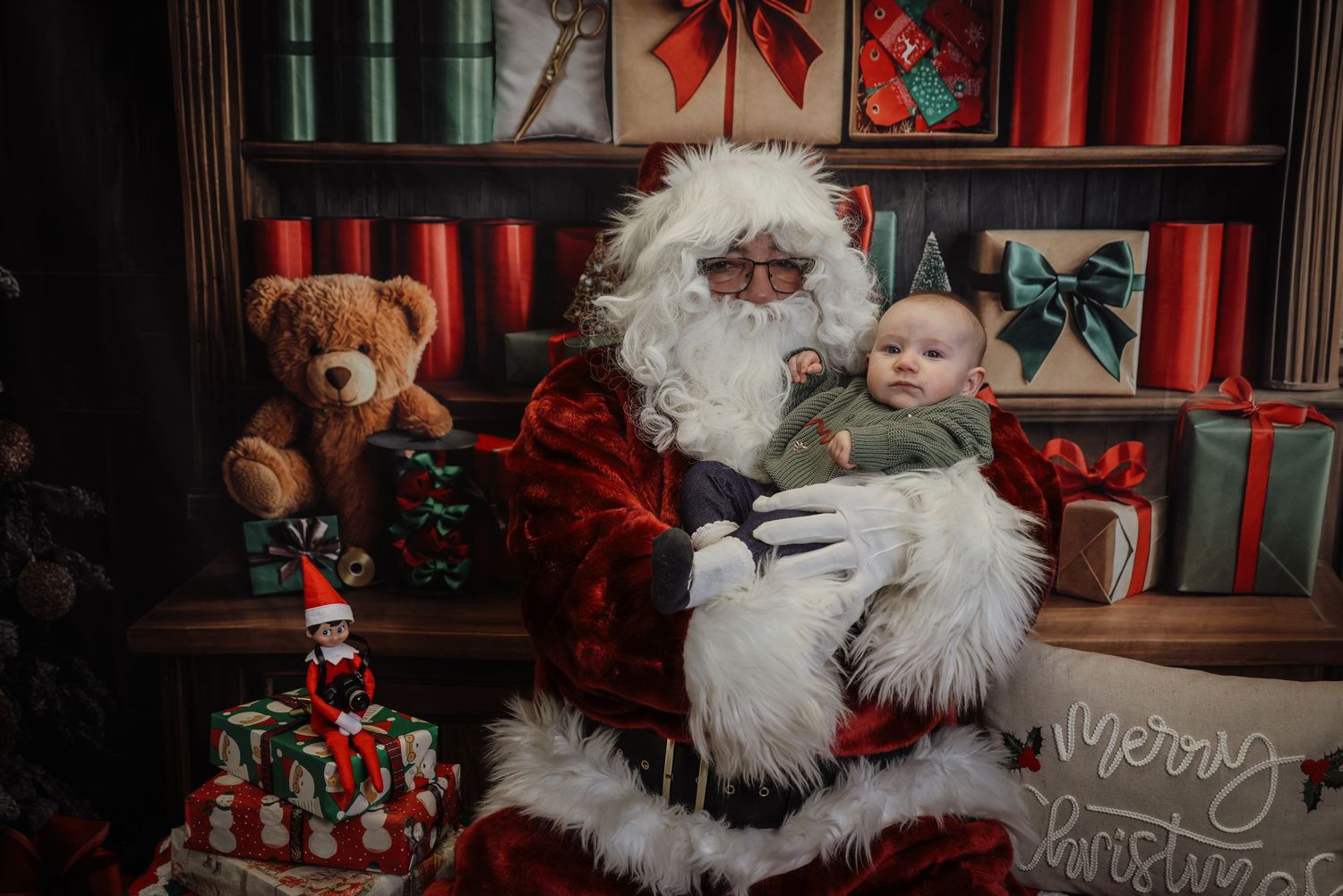 A festive Christmas scene with Santa Claus and teddy bears arranged in a cozy holiday display with red decorations.