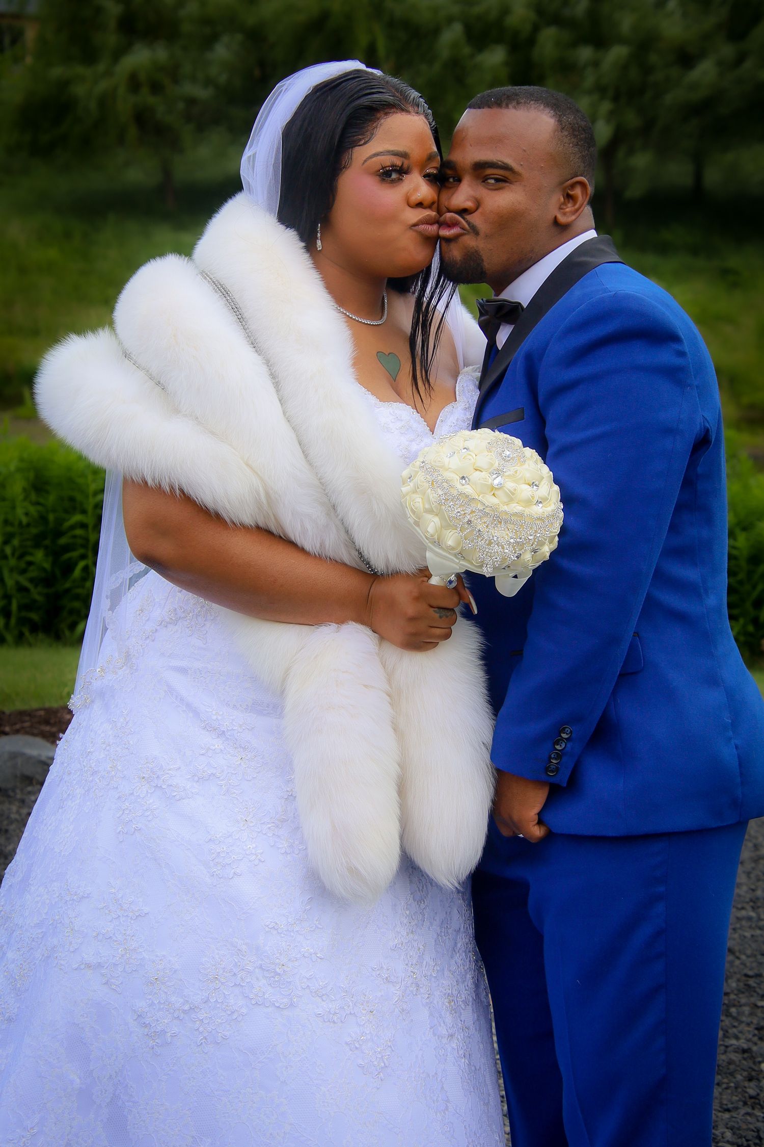 A romantic wedding couple in a white dress and blue suit share intimate moments during their outdoor photo session.