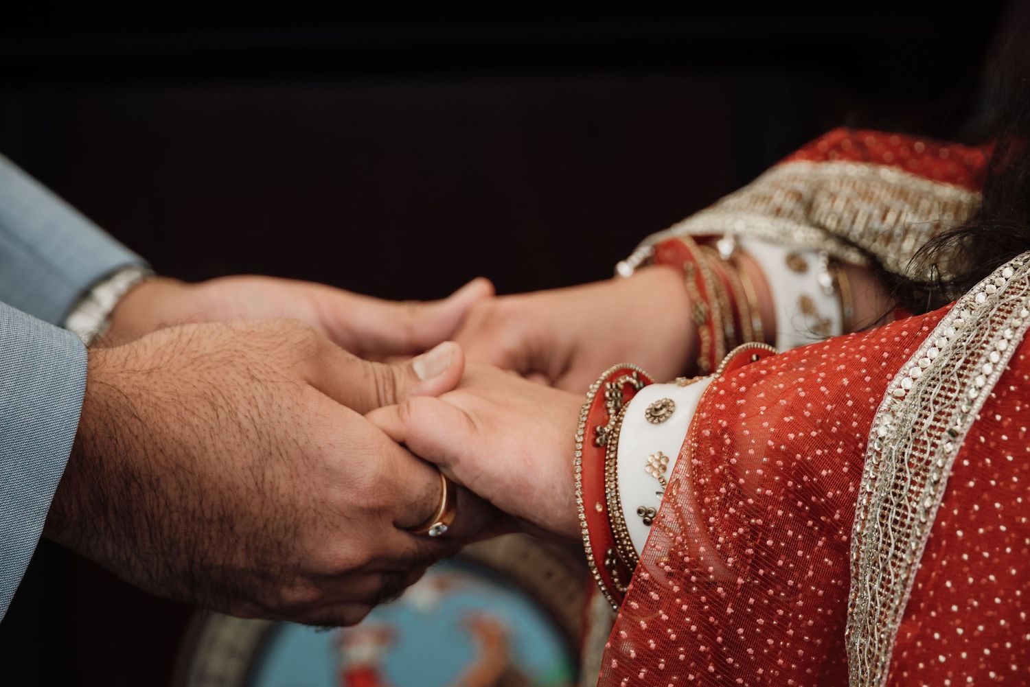 Close-up details of ornate red and gold embroidered Indian wedding sari fabric with intricate traditional patterns.