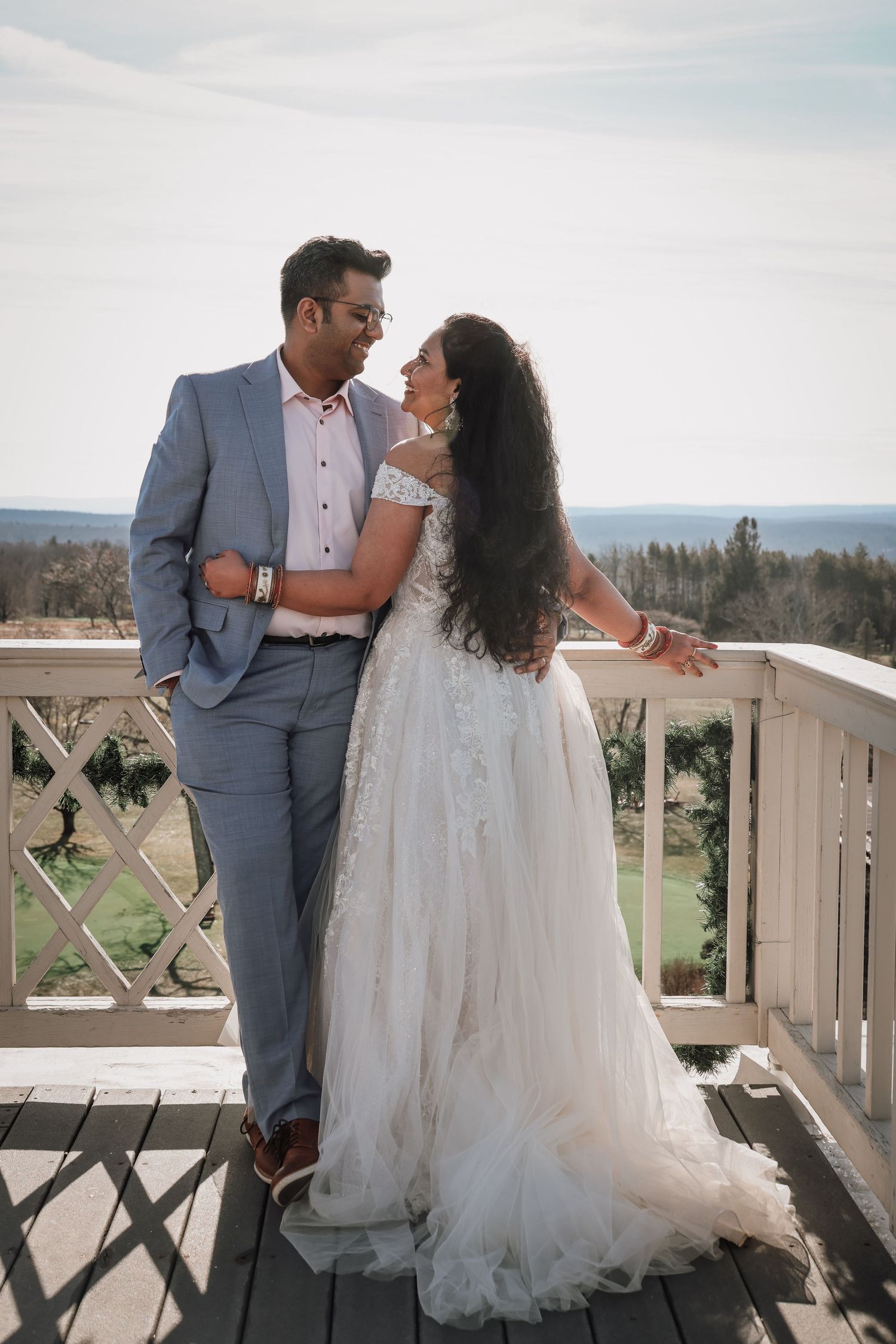 A romantic wedding couple shares intimate moments on a rustic balcony overlooking scenic mountain views.