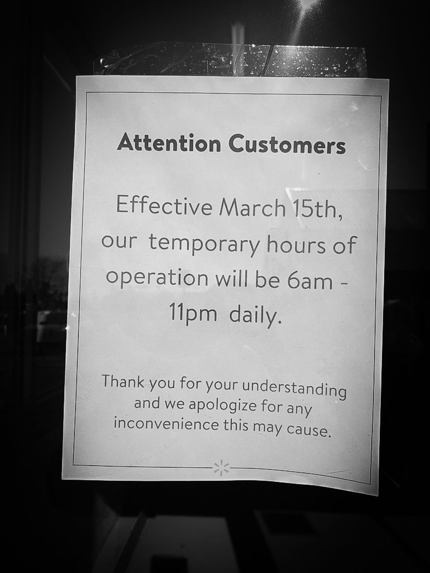 Black and white photo of business hours notice showing new temporary hours from 6am to 11pm daily starting March 15th.