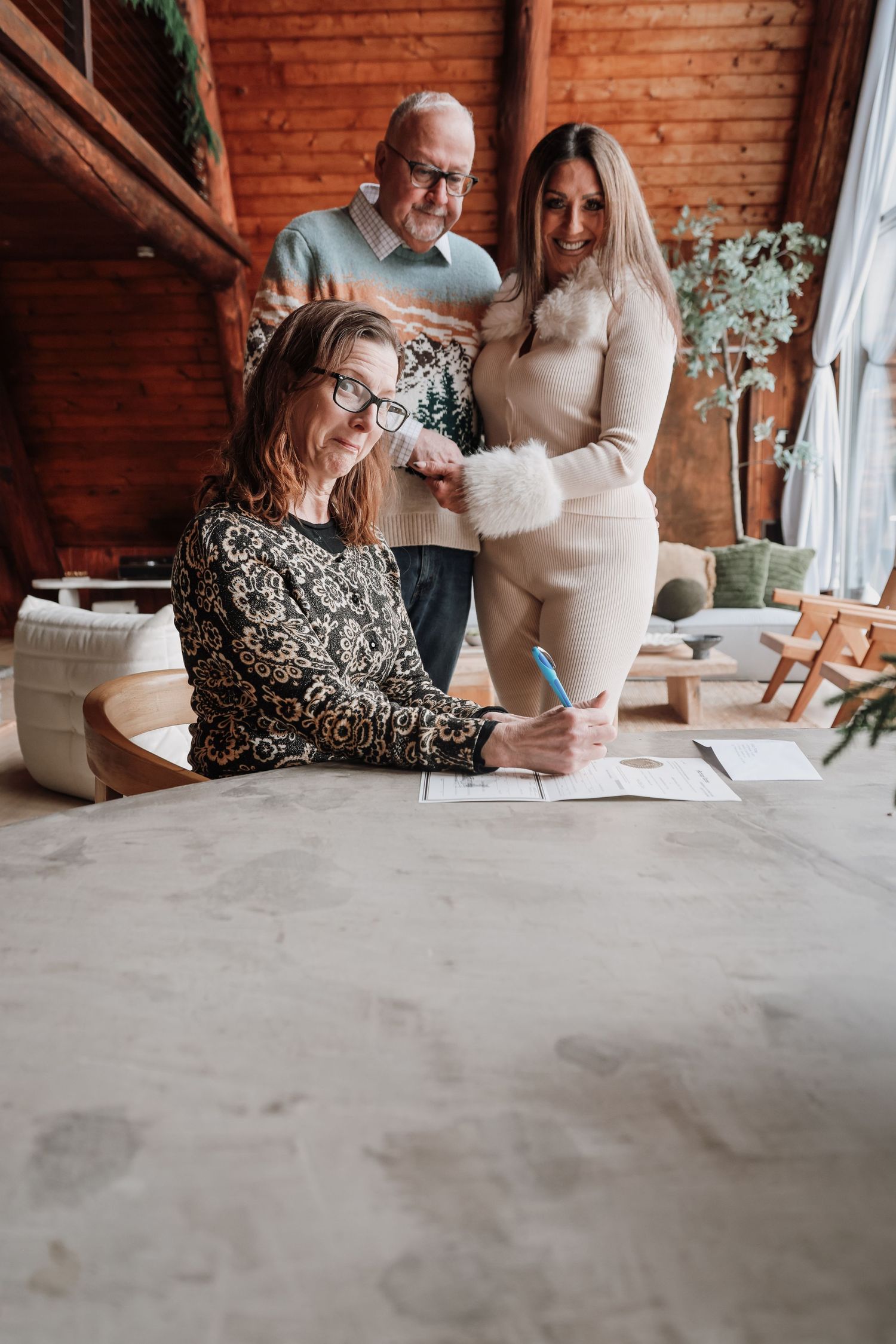 Two people sit together at a rustic brick venue reviewing documents at a table with white floral arrangements.