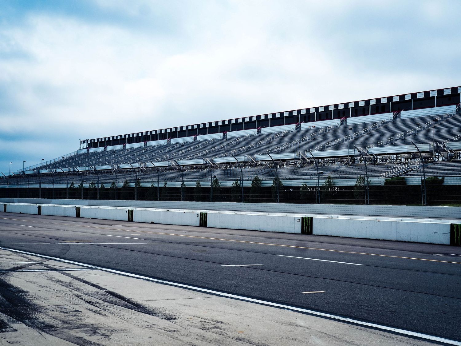 Empty grandstand seating and track barrier at a motorsports racing venue on an overcast day.