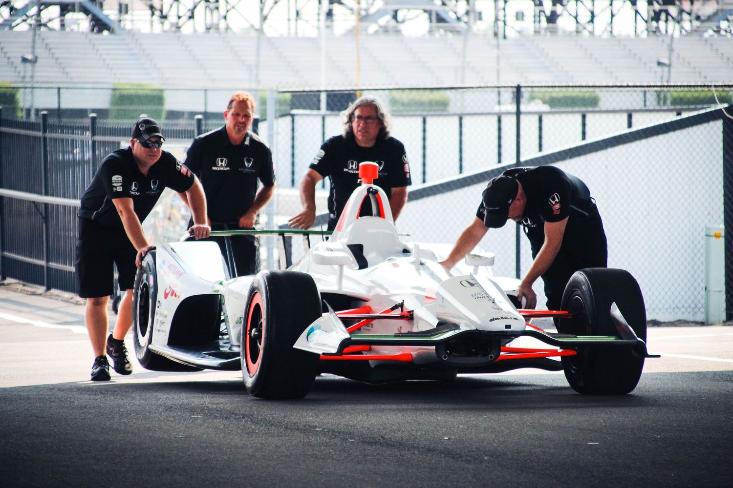 Formula 1 pit crew members perform tire changes and maintenance on a race car during a pit stop.