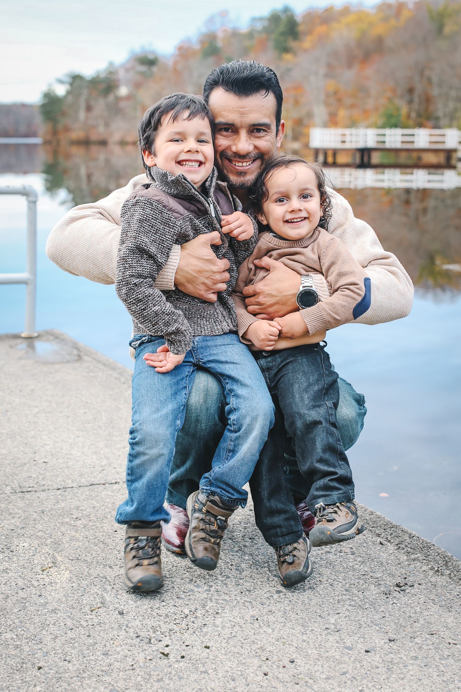A heartwarming series of candid moments between a parent and child playing together by a lake on an autumn day.