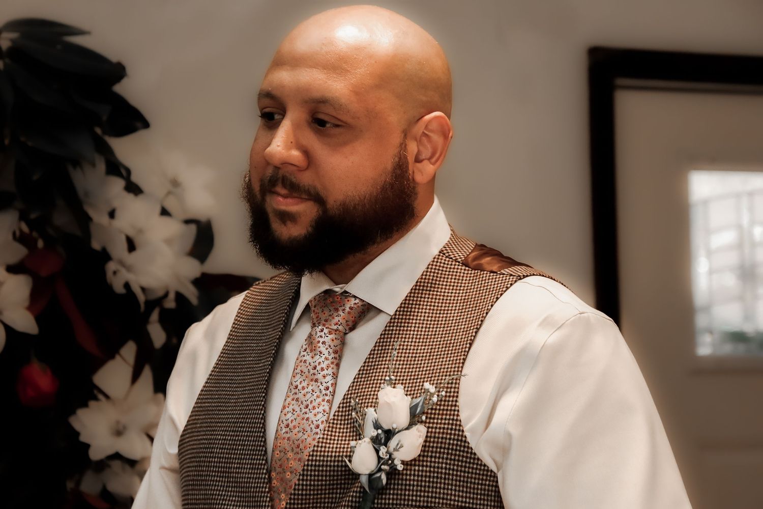 A person in a white dress shirt and vest stands in an indoor setting during what appears to be a formal event.