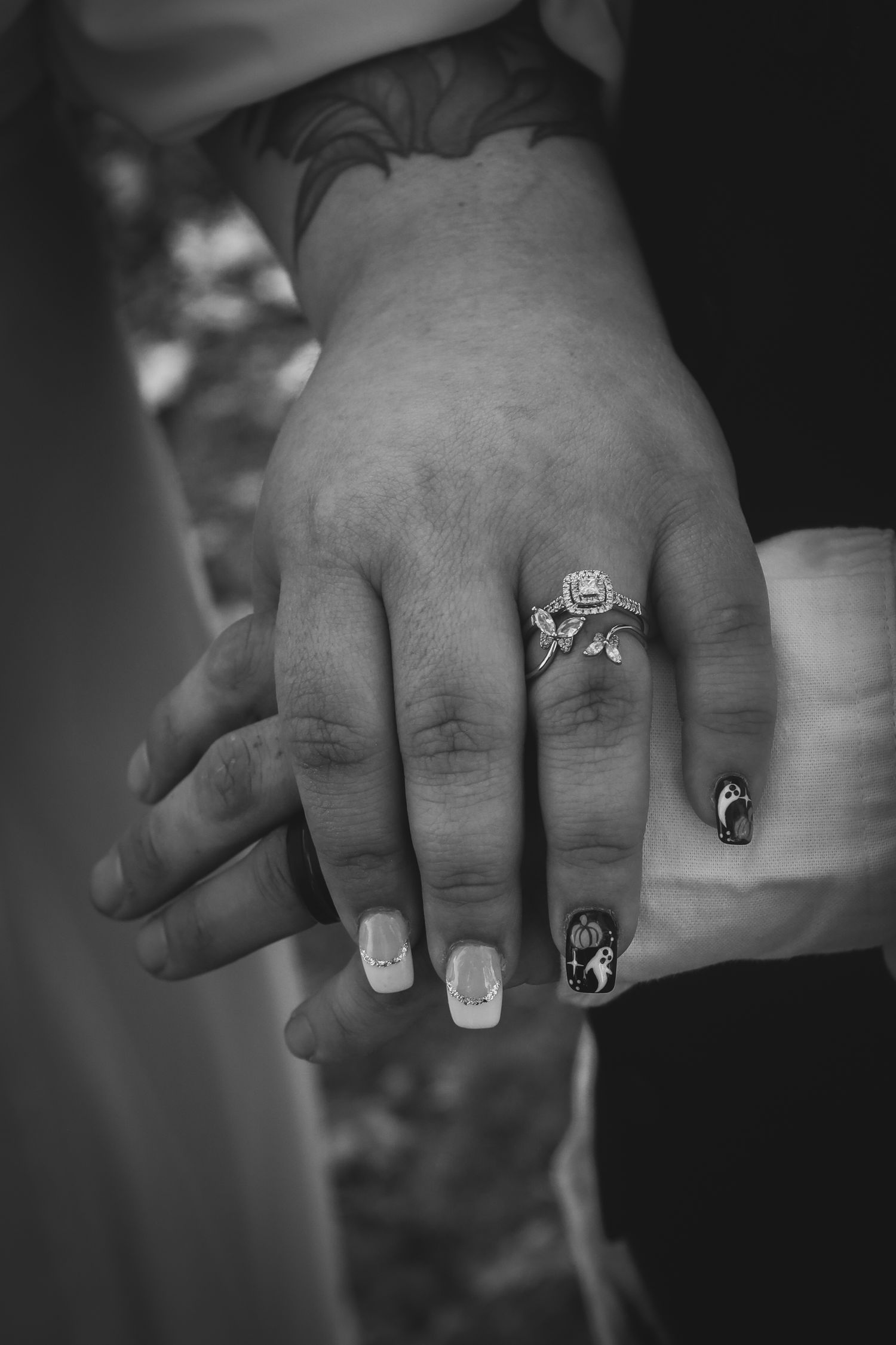 A series of black and white close-up photographs showing hands wearing various decorative rings against a dark background.