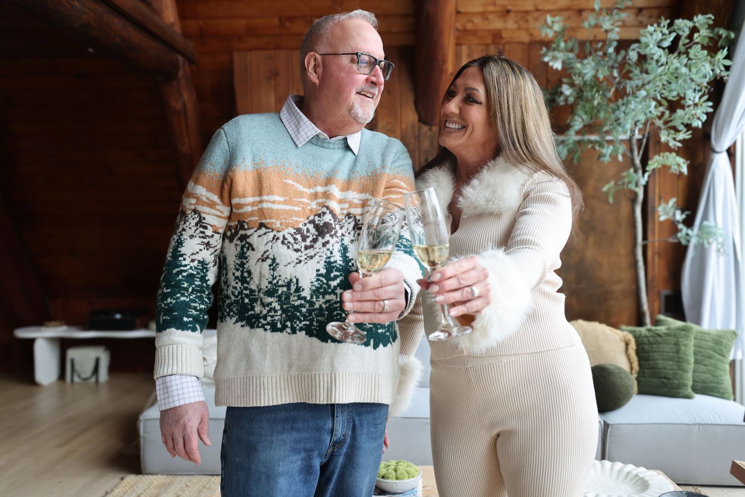 A couple laughs and smiles while enjoying drinks together at a rustic indoor venue.