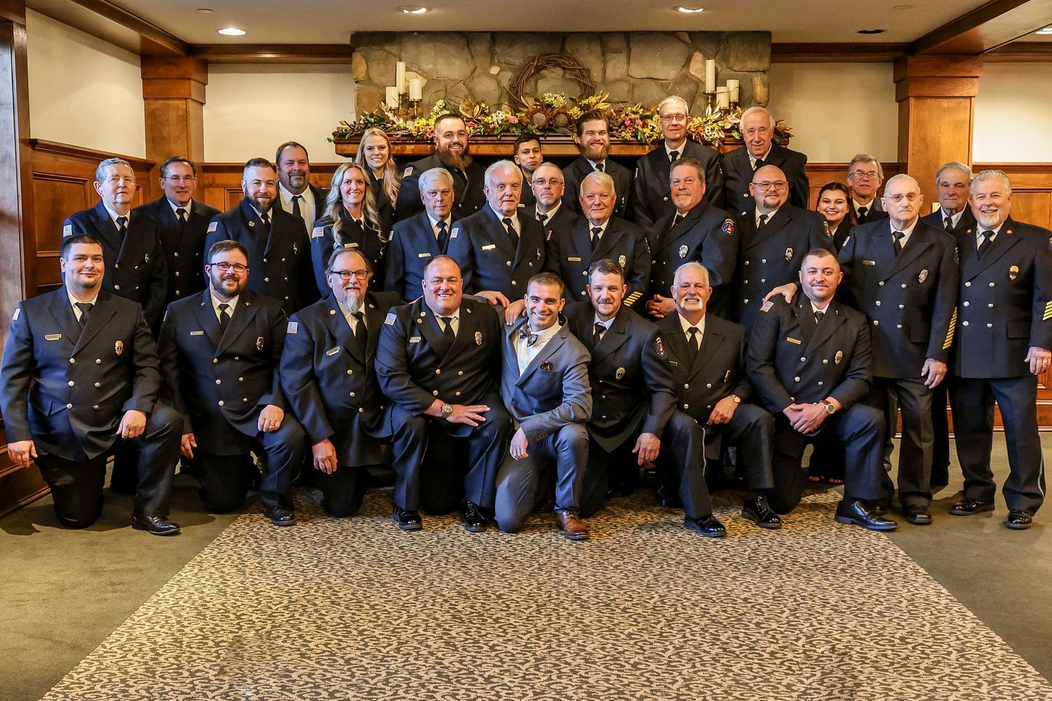 Large panoramic group photo of uniformed service members standing together in a formal indoor setting.