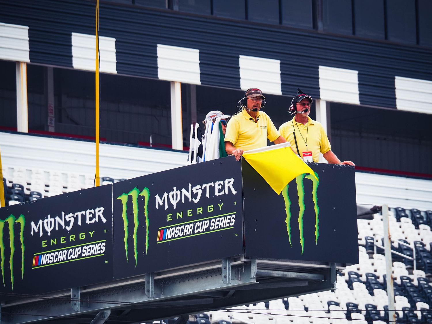 A motorcycle racer in yellow and black leathers leans into a turn on a racing circuit with Monster Energy branding visible.