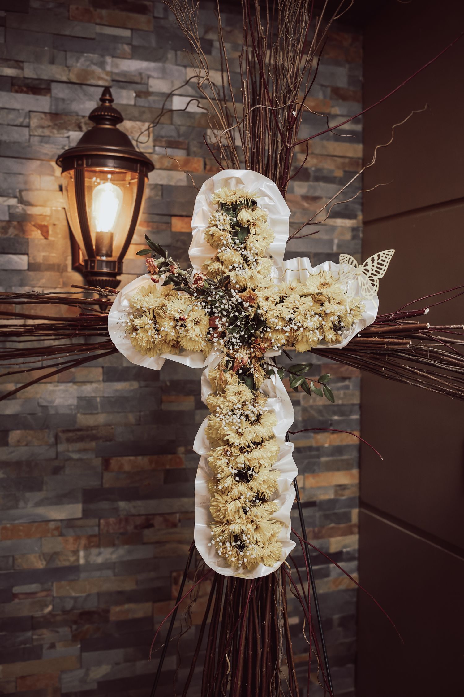 Rustic wedding decor featuring white hydrangea bouquets with twigs against stone wall and vintage lantern lighting.