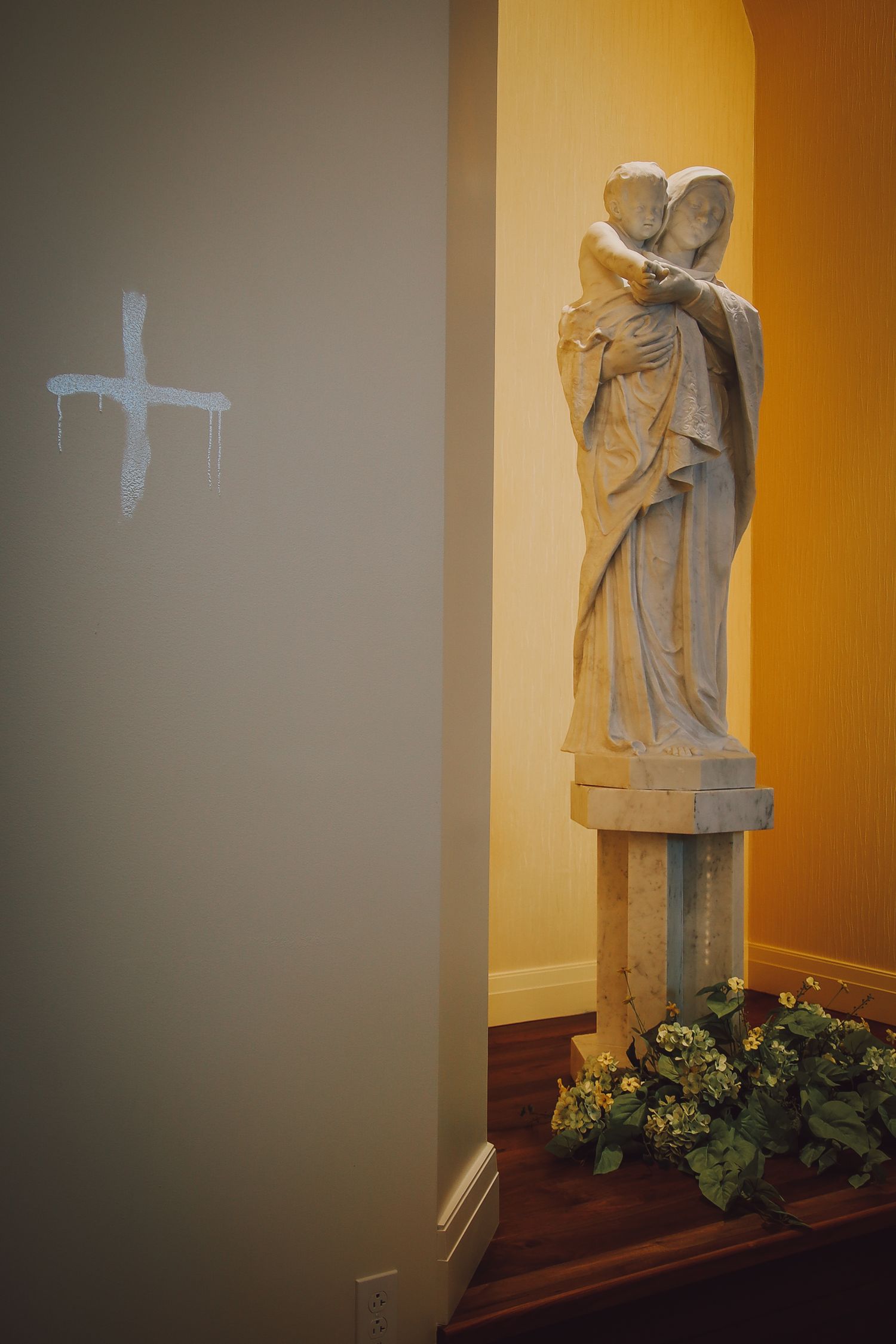 A series of four photos showing a white religious statue displayed on a wooden shelf with yellow-lit walls in the background.