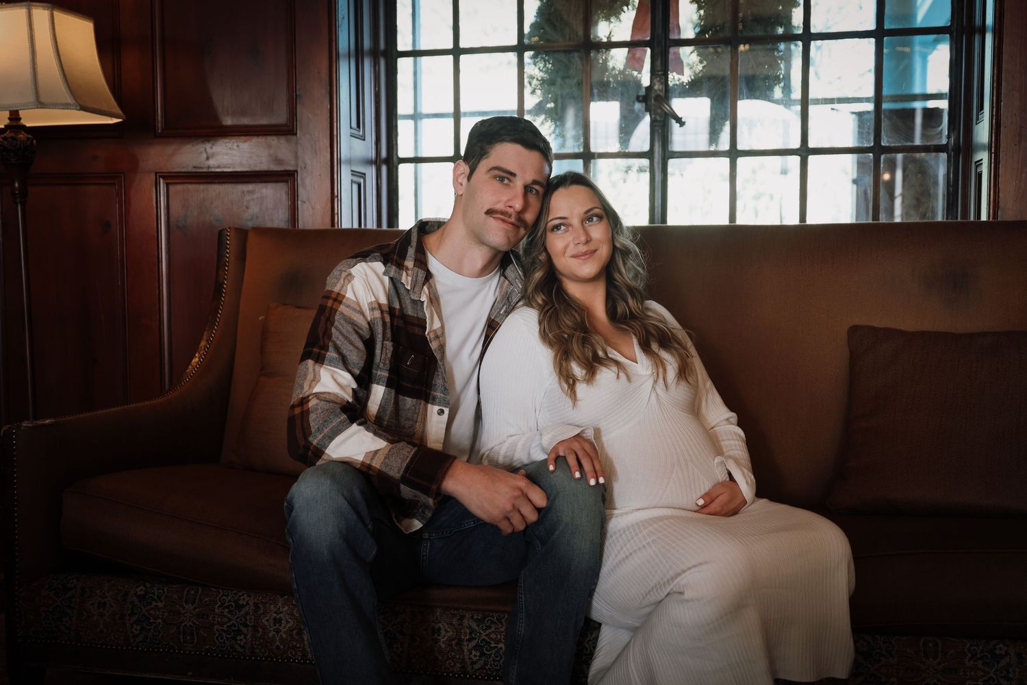 A couple shares intimate moments in a rustic indoor setting with natural window lighting.