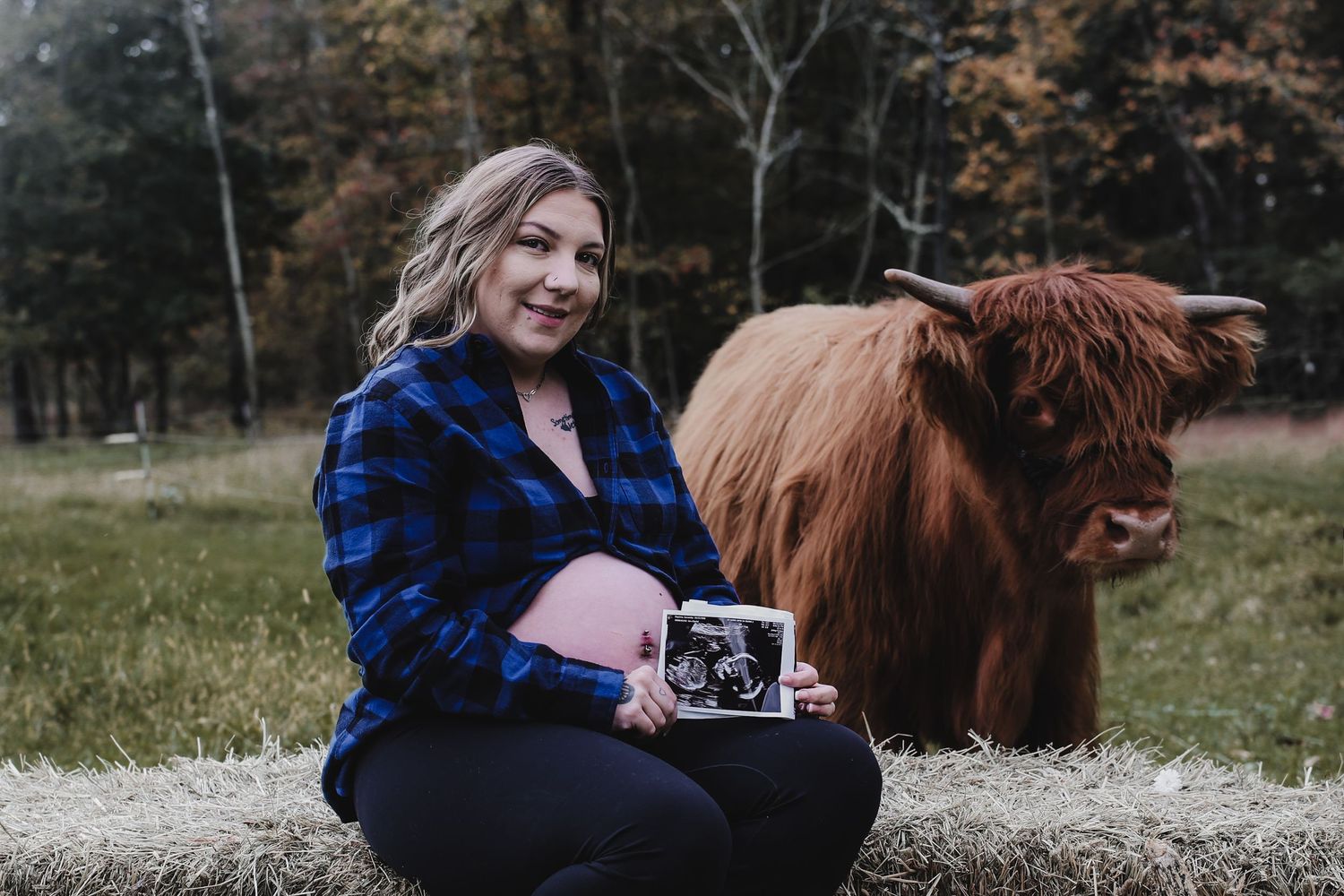 A person in a blue plaid shirt takes photos with a vintage camera while posing with a brown horse in a fall meadow.