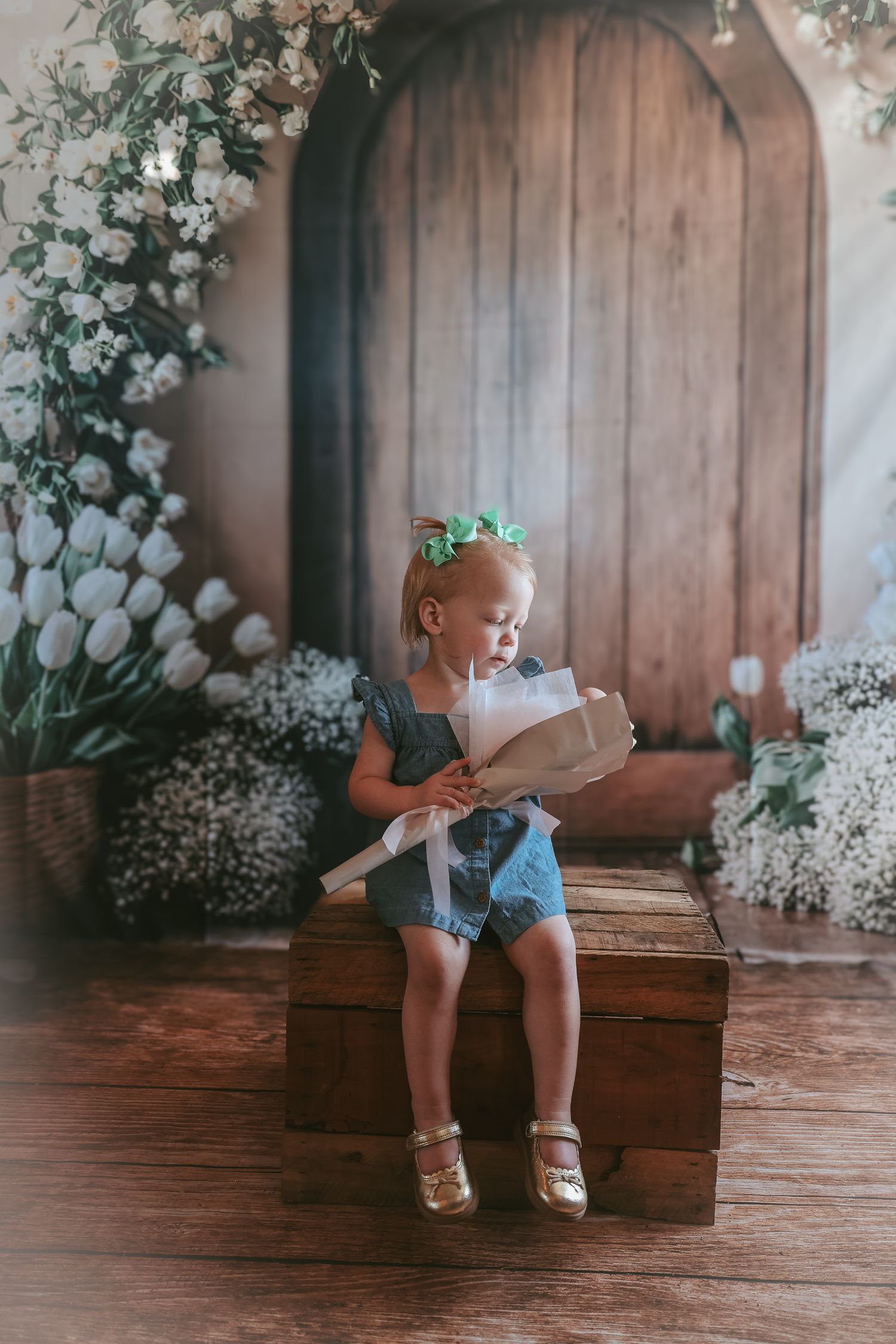 A series of photos showing a small child sitting on a rustic wooden chest surrounded by white floral decorations.