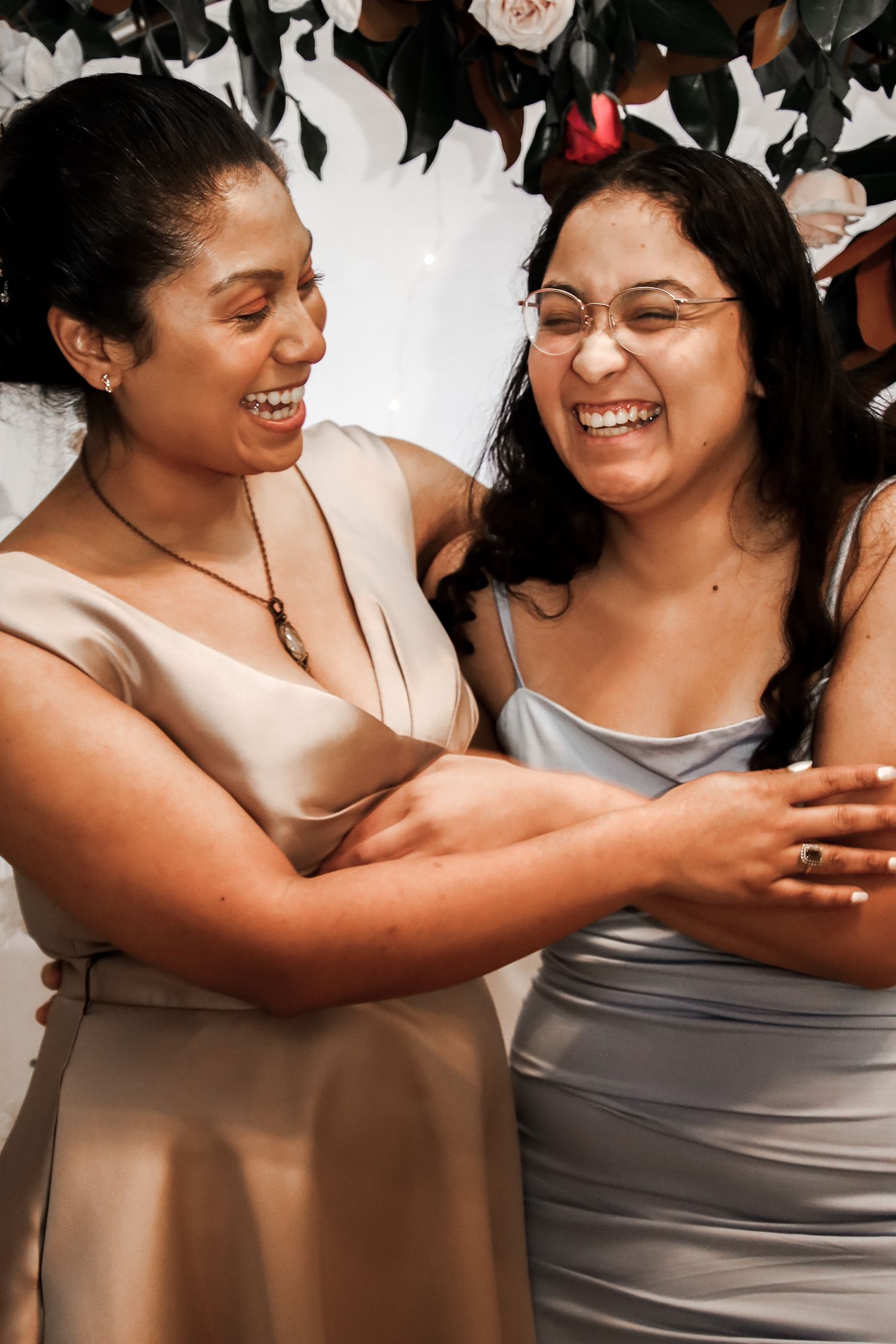 Two friends share a joyful moment together while wearing casual tank tops in warm lighting.
