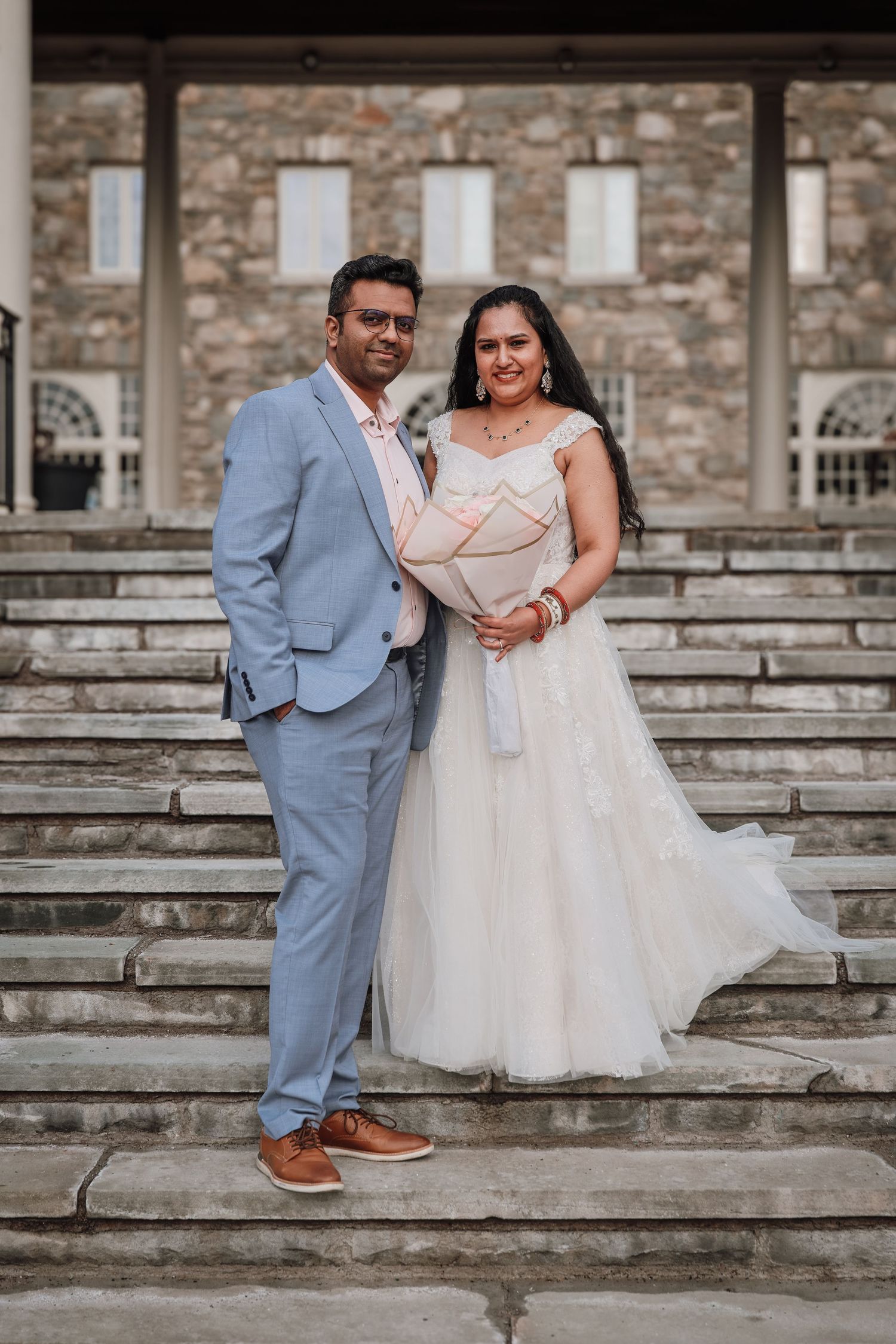 Newlywed couple sits together on stone steps in romantic wedding portrait series.