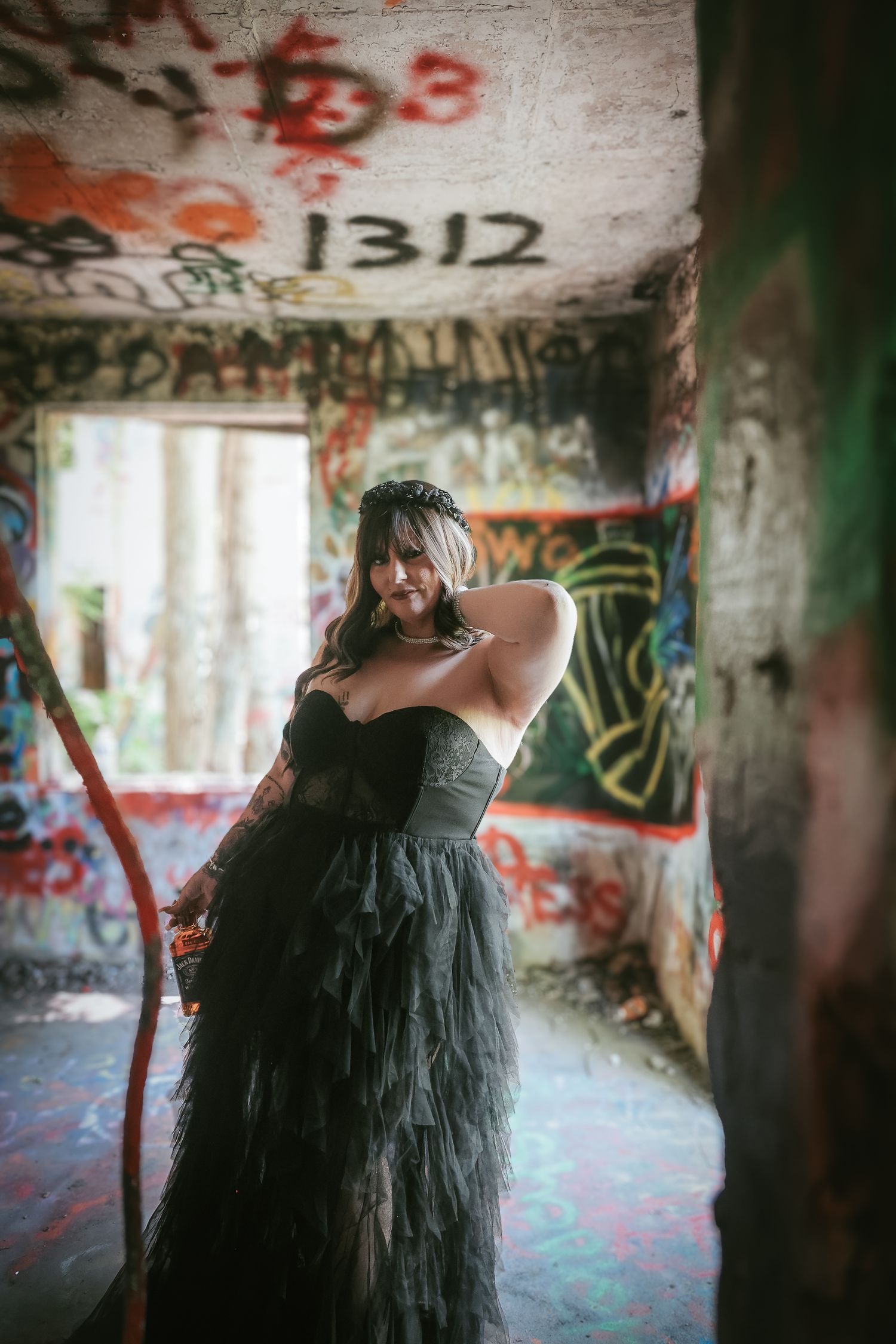 A figure with long flowing black hair dances expressively in an abandoned graffiti-covered space.