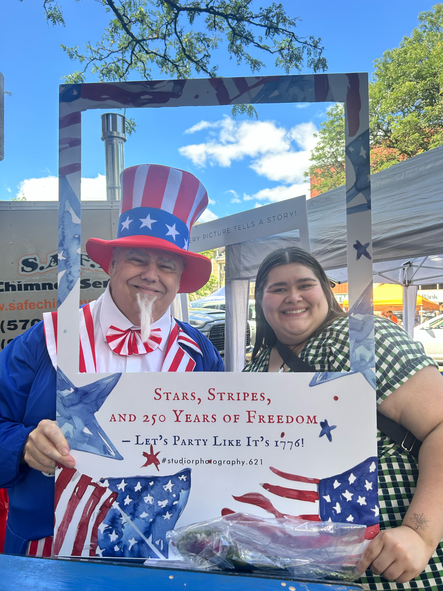 Several people wearing patriotic American flag clothing and Uncle Sam hats celebrate at an outdoor Fourth of July event.