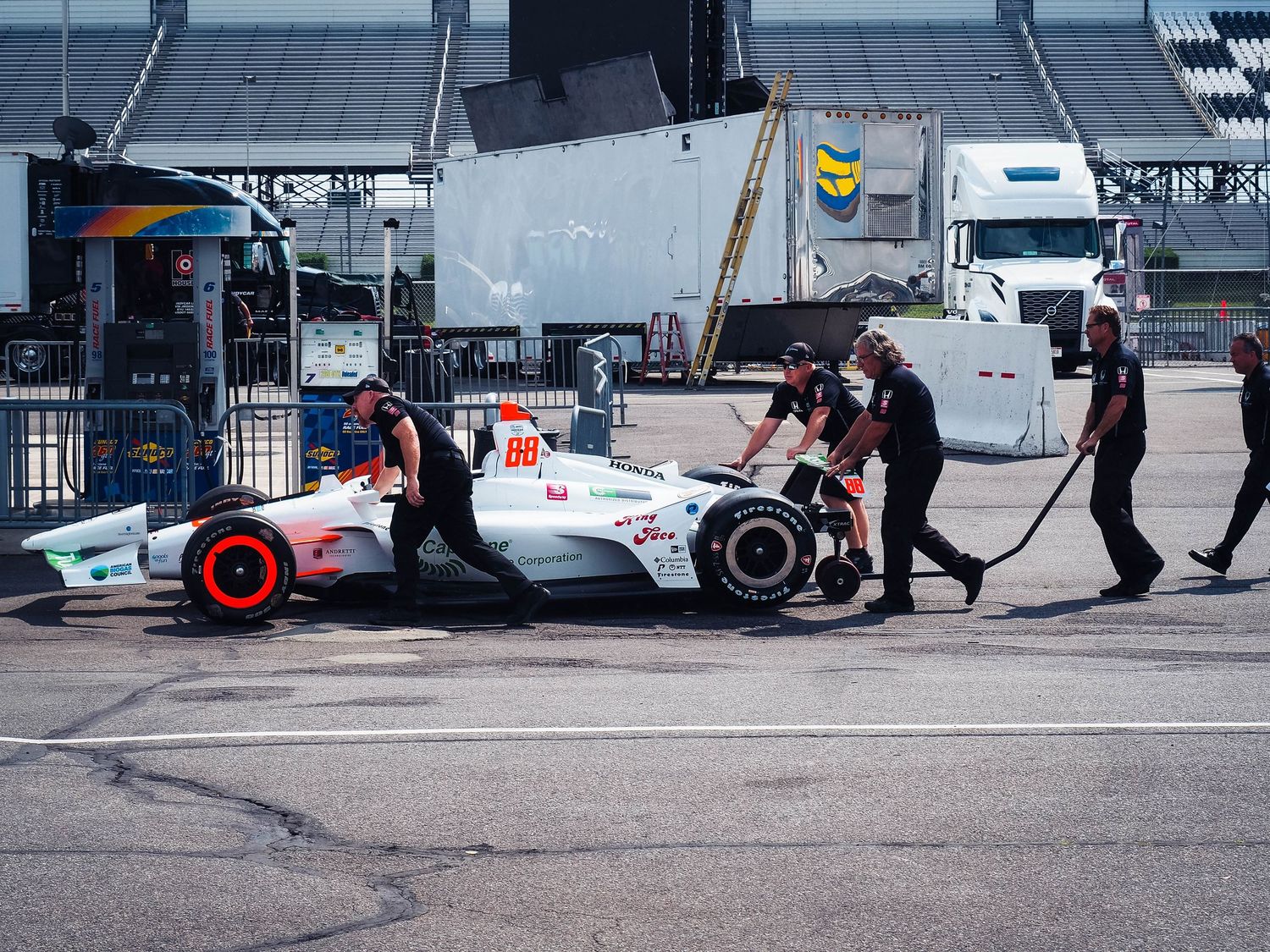 Racing pit crew members perform quick tire change during motorsport competition pit stop.