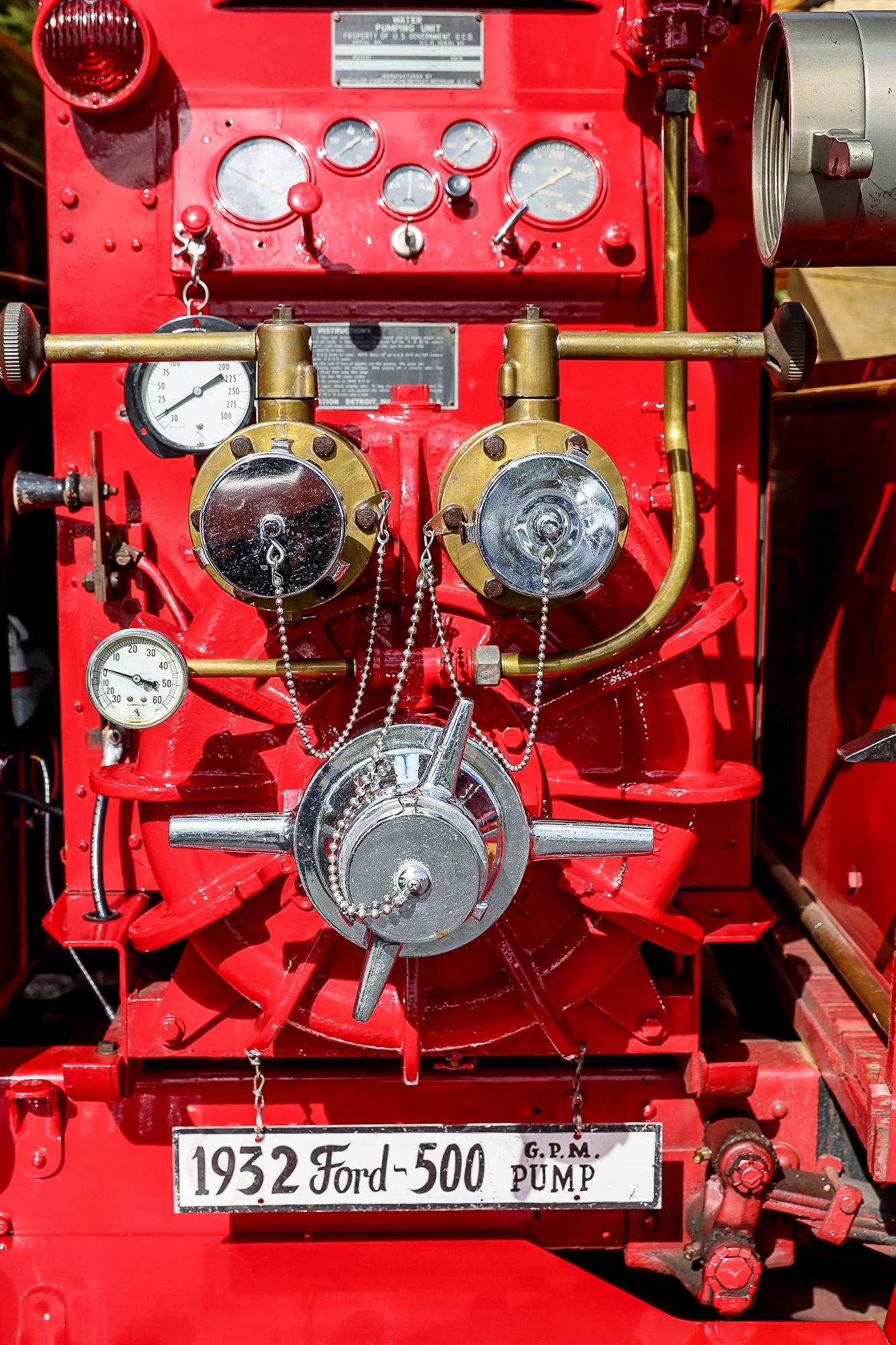 Close-up of a vintage 1932 Ford 500 GPM fire truck pump panel with brass fittings and pressure gauges.