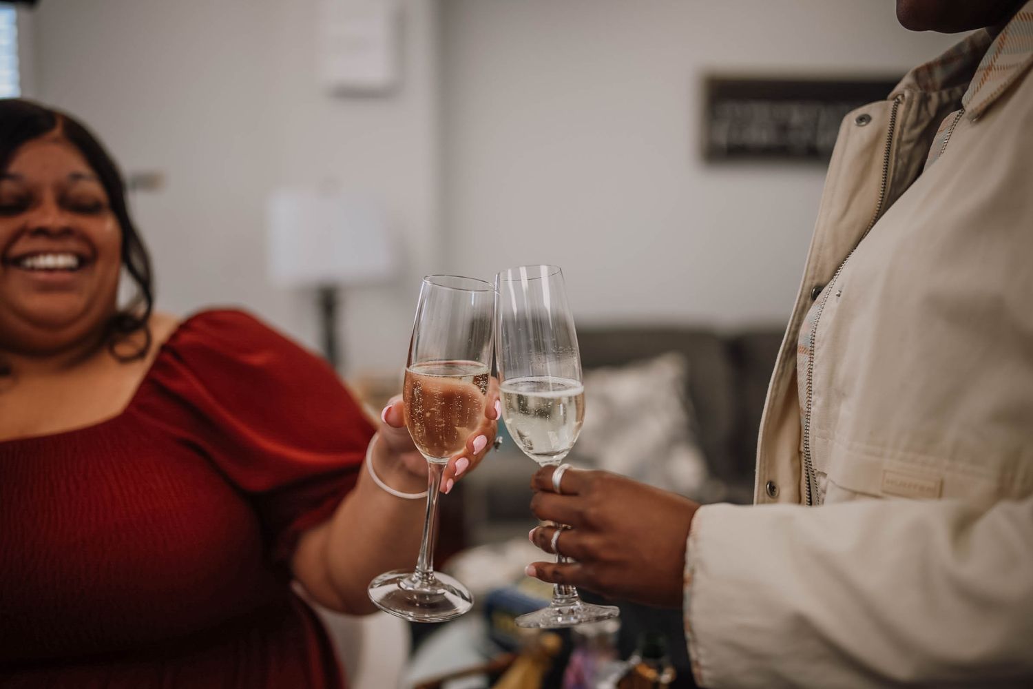 Two women toasting with champagne glasses filled with rose and white wine at a celebration.