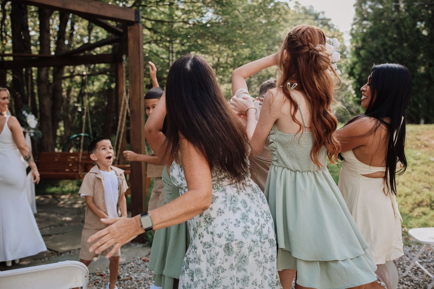 Group of people in green and white dresses dancing and celebrating at an outdoor summer gathering.