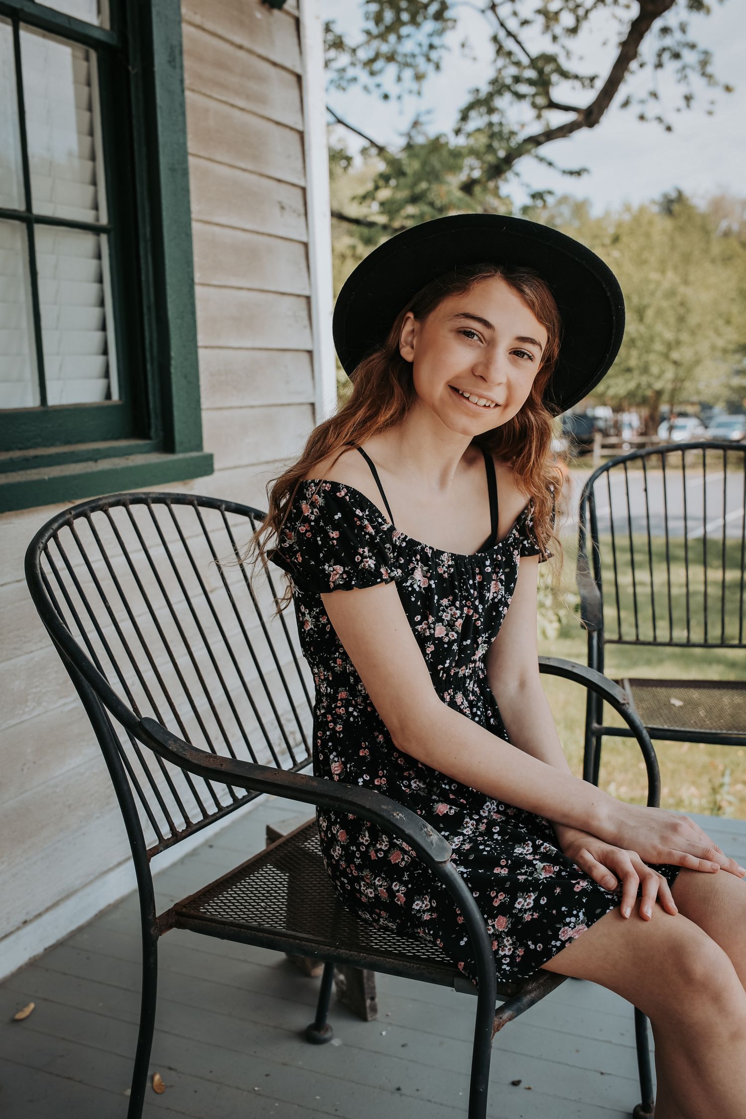 A person in a floral dress sits on a black metal porch bench in a series of casual outdoor portraits.