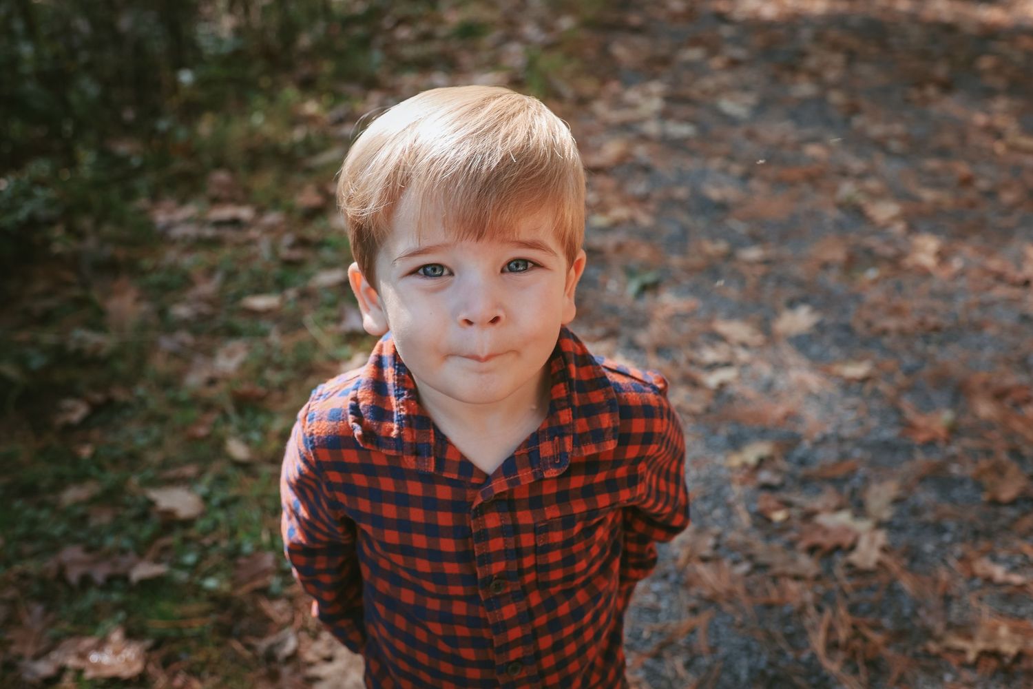 A series of candid outdoor portraits showing a young child in a red plaid shirt making playful expressions.