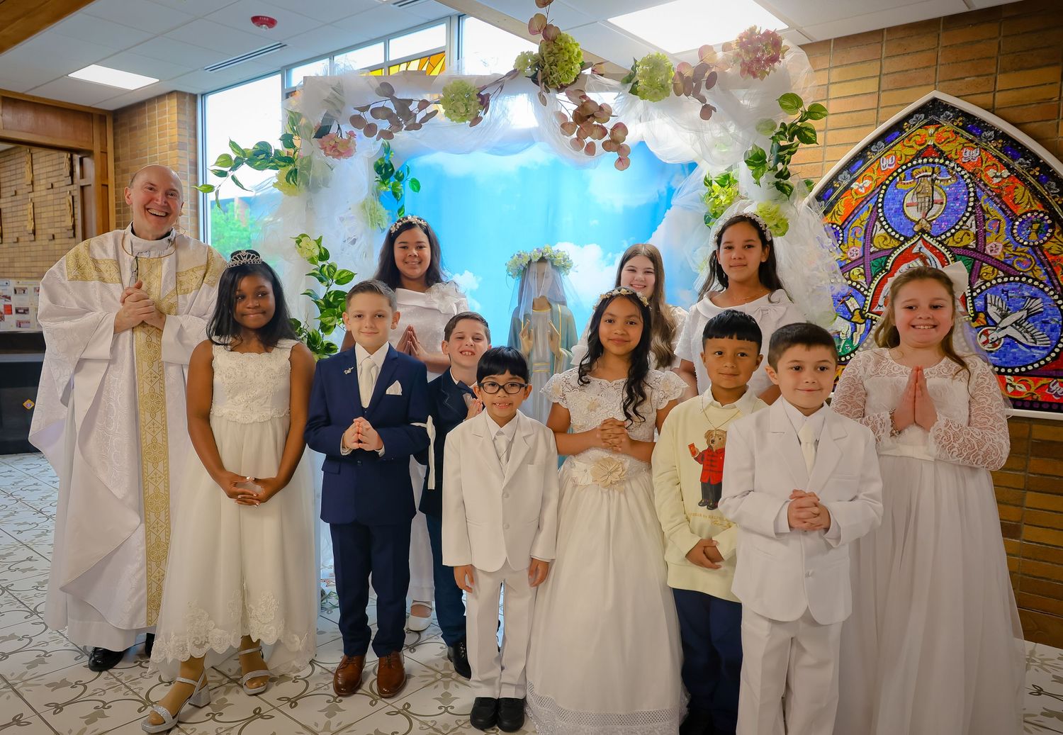 Group of children wearing white formal attire gather together at a religious ceremony or celebration.