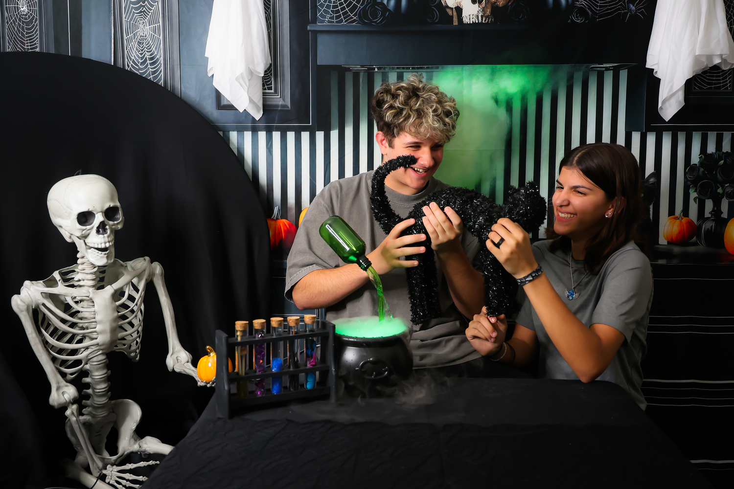 A plastic skeleton decoration sits at a bar counter while people socialize in the dark background with green lighting.