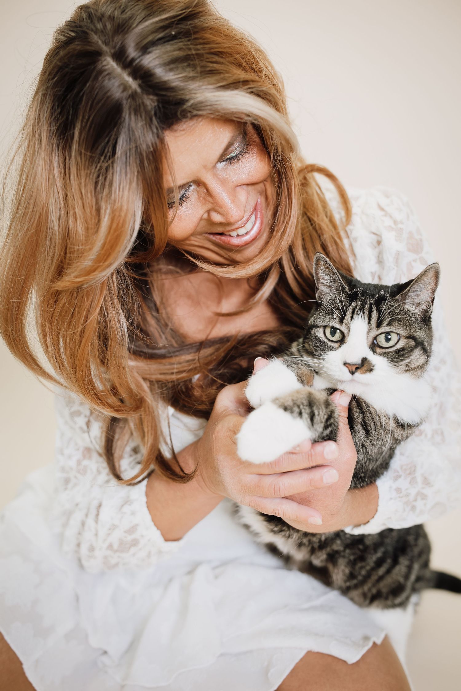 A person in a white top cuddles and plays with their grey and white cat in a series of affectionate poses.