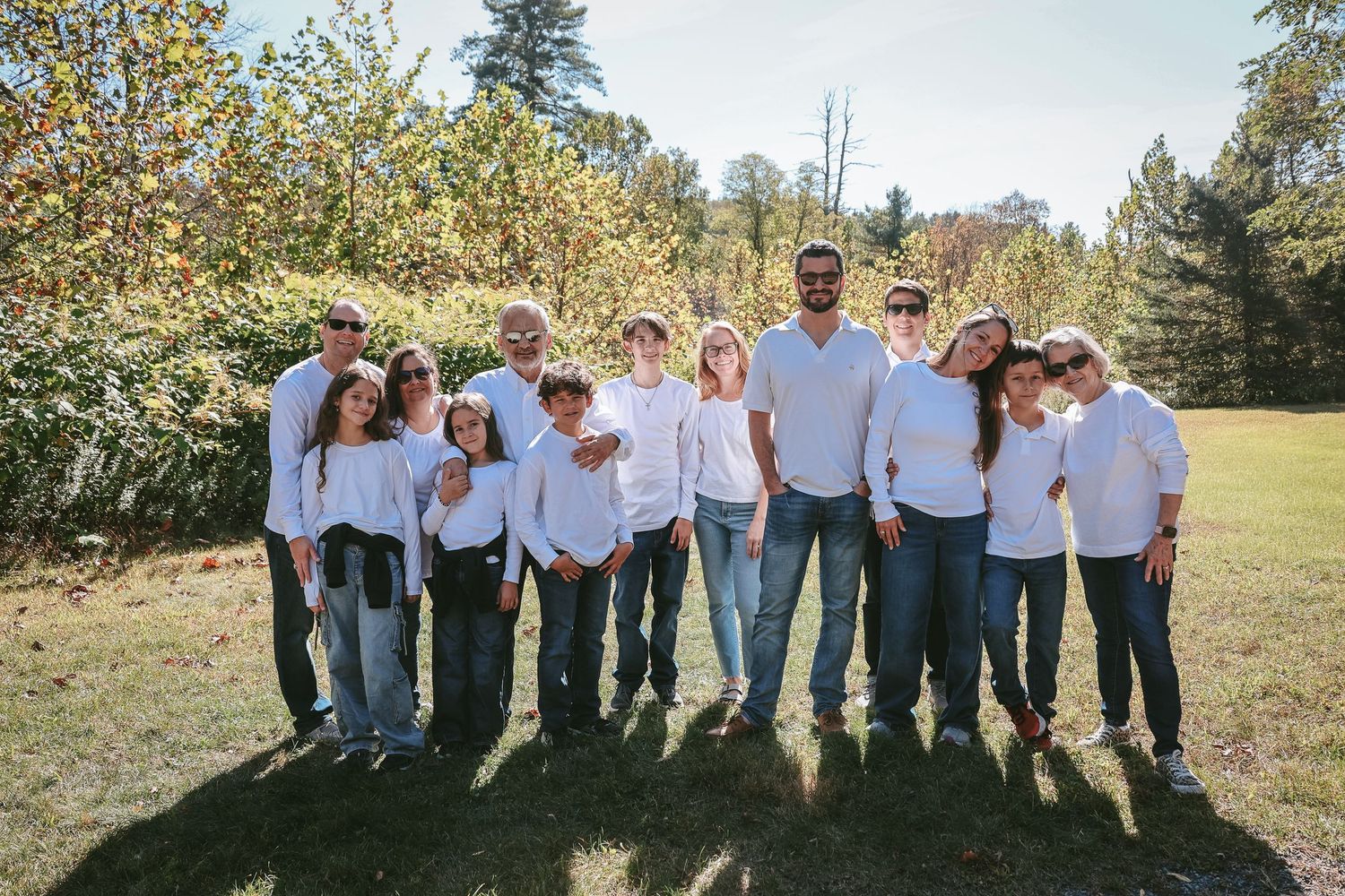 A group in coordinated casual outfits stands together outdoors in a field on a sunny autumn day.