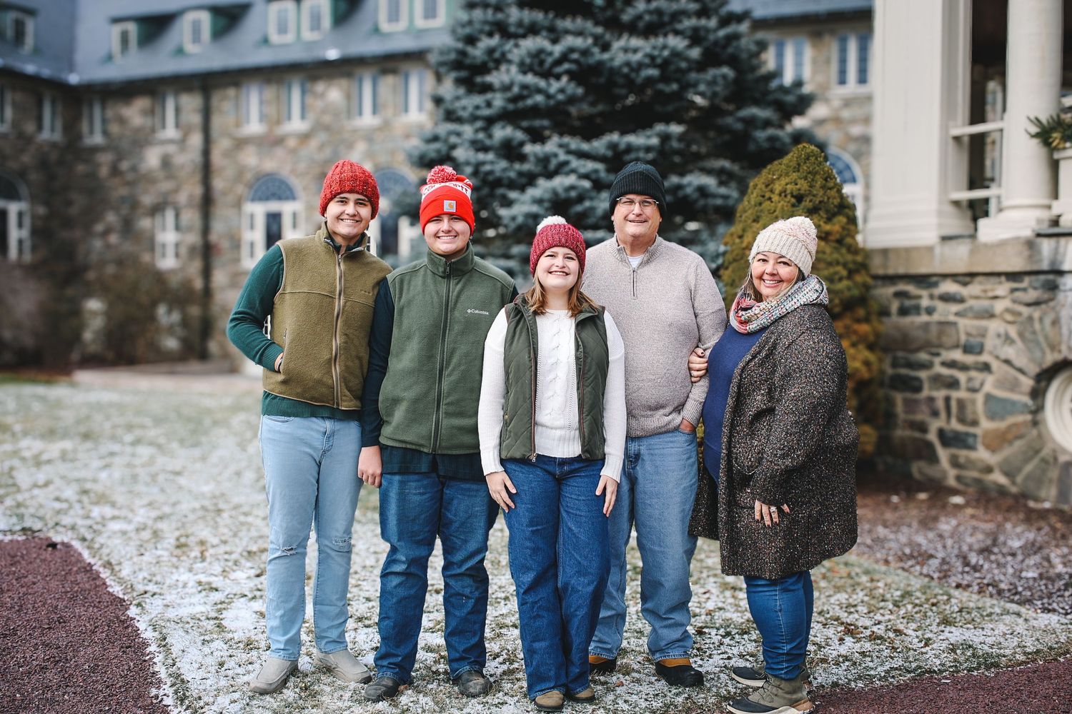 A group of people walk together through a snowy winter landscape near stone buildings.